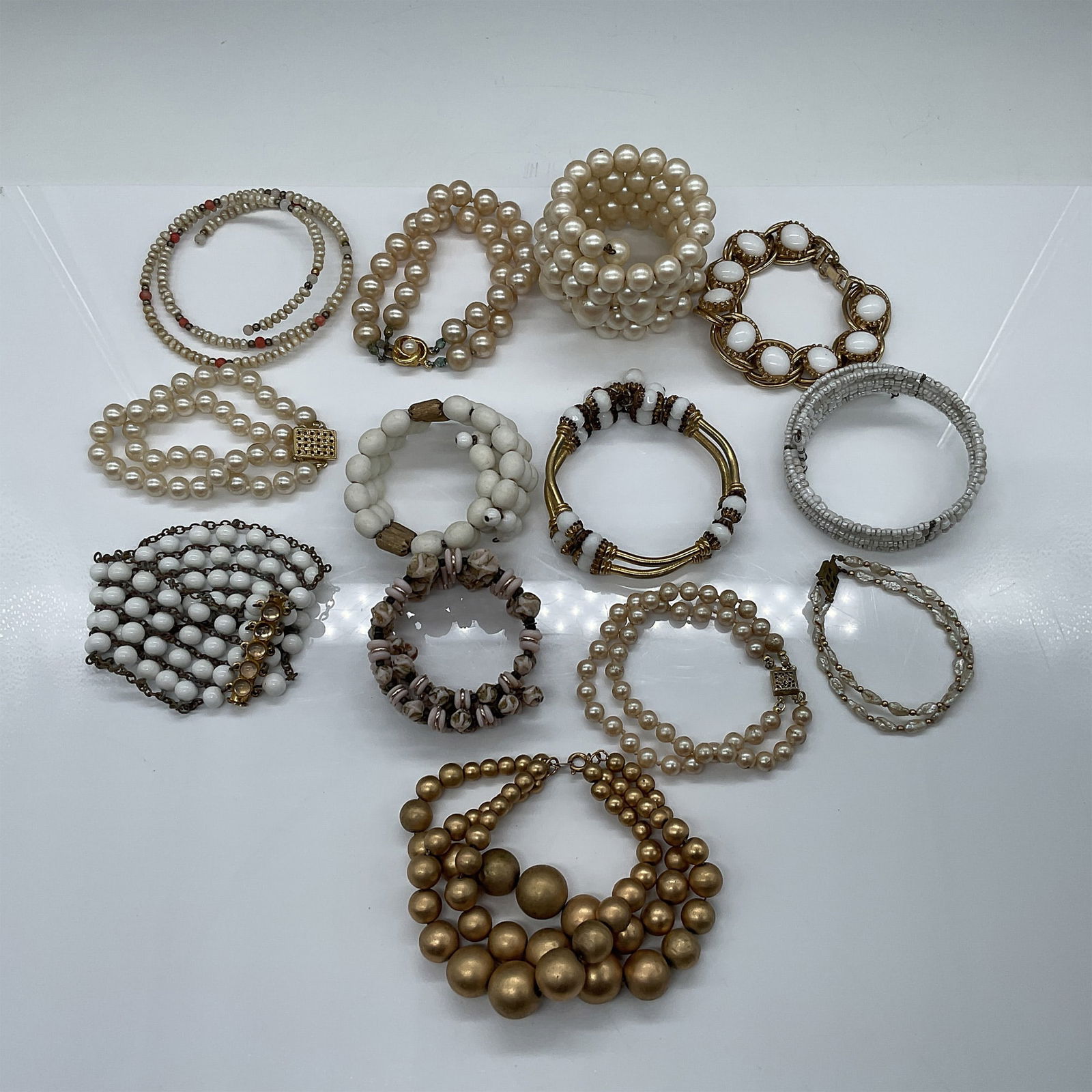 13pc Vintage Jewelry, Beaded Bracelets and Bangles: A collection of 13 vintage jewelry pieces featuring a variety of beaded bracelets and bangles. The assortment includes faux pearl designs and metallic accents. Largest piece measures 2.25"H. This dive