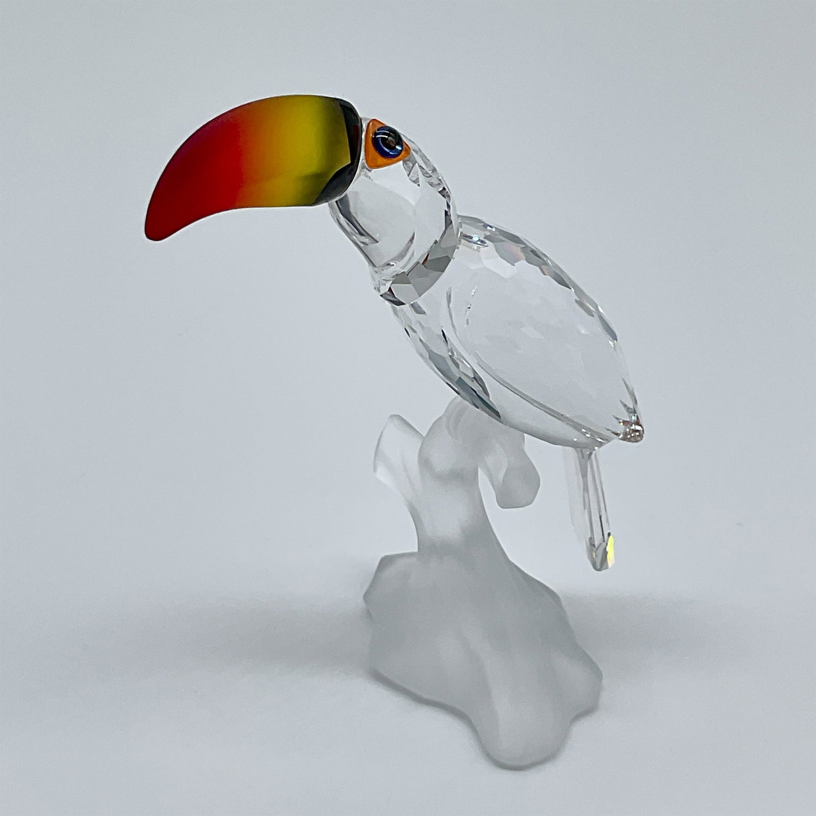 Swarovski Crystal Figurine, Toucan: This stunning Swarovski crystal "Toucan" figurine, designed by Michael Stamey, was introduced in 1999 and produced until 2009. This version features a vibrant, frosted orange and yellow beak, distinct