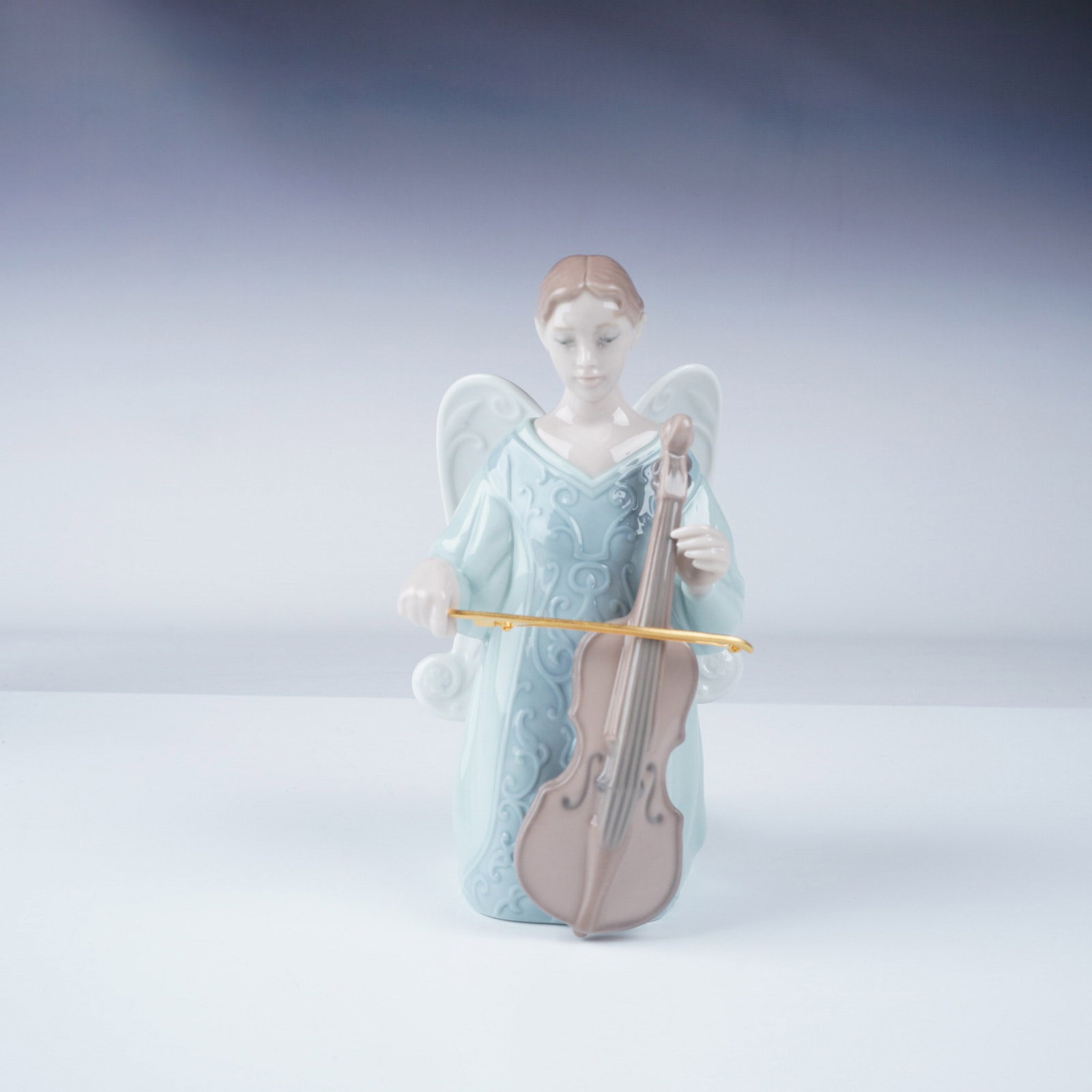 Lladro Porcelain Figurine, Cello Cantata 1008183: Elegant Lladro porcelain figurine titled Cello Cantata, designed by Miguel Angel Santaeulalia. This exquisite piece depicts an angel gracefully playing the cello, capturing a moment of musical devotio