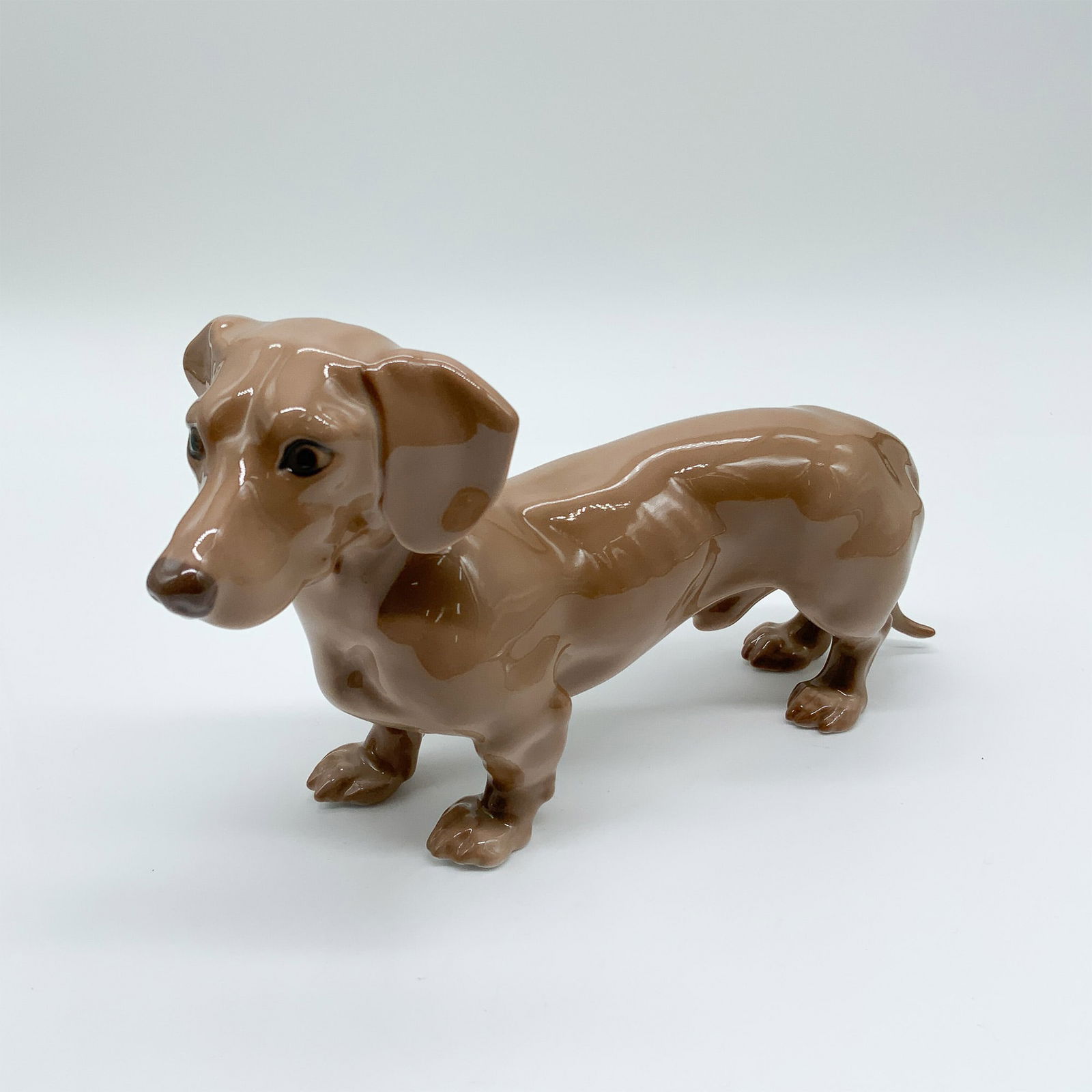 Bing & Grondahl Porcelain Dachshund Figurine, Model 1752: Bing & Grondahl porcelain dachshund figurine, model 1752, featuring a glossy brown glaze and lifelike details. Marked on the underside with the B&G backstamp. A fine example of the Danish manufacturer