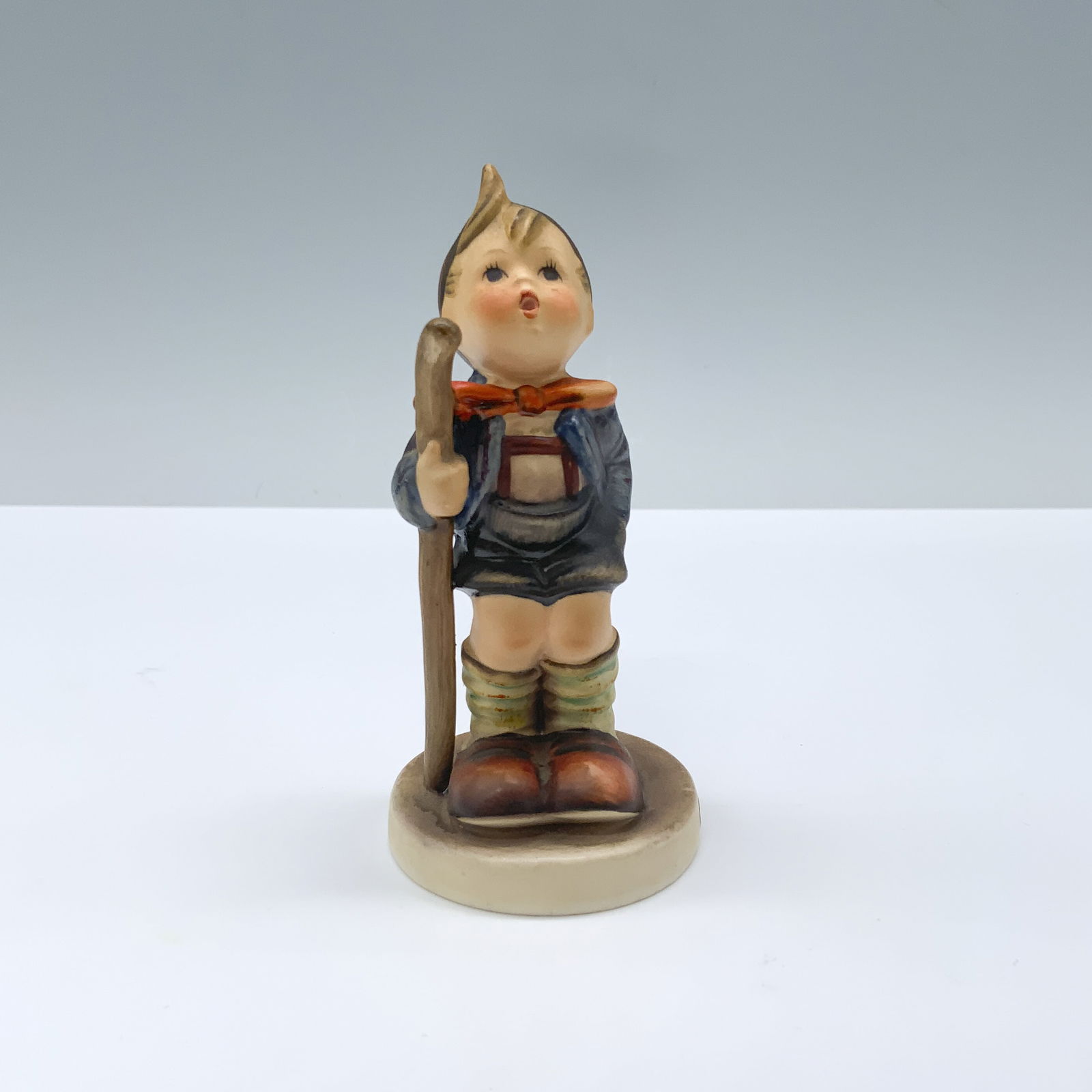 Goebel Hummel Porcelain Figurine, Little Hiker: Young boy dressed for hiking, holding his walking stick. Goebel Hummel backstamp. Issued: 20th century Dimensions: 2"W x 4.25"H Country of Origin: Germany