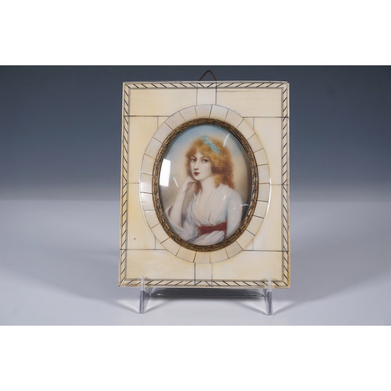 Antique Miniature Portrait in Bone Frame: An exquisite antique miniature portrait painting depicting a young woman with flowing golden hair, dressed in a white gown with a red sash. The finely detailed portrait is set within an oval brass fra