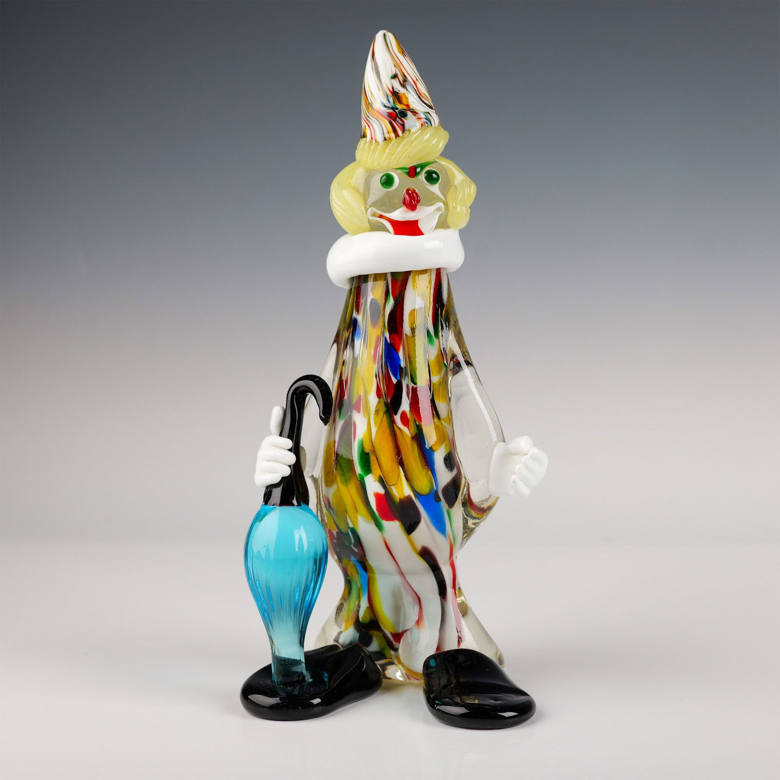 Murano Glass Clown Figurine with Umbrella: This colorful Murano glass clown figurine stands at 11.5" in height and showcases the vibrant art of Venetian glassmaking. The clown features a playful design with swirling colors in yellow, red, blue