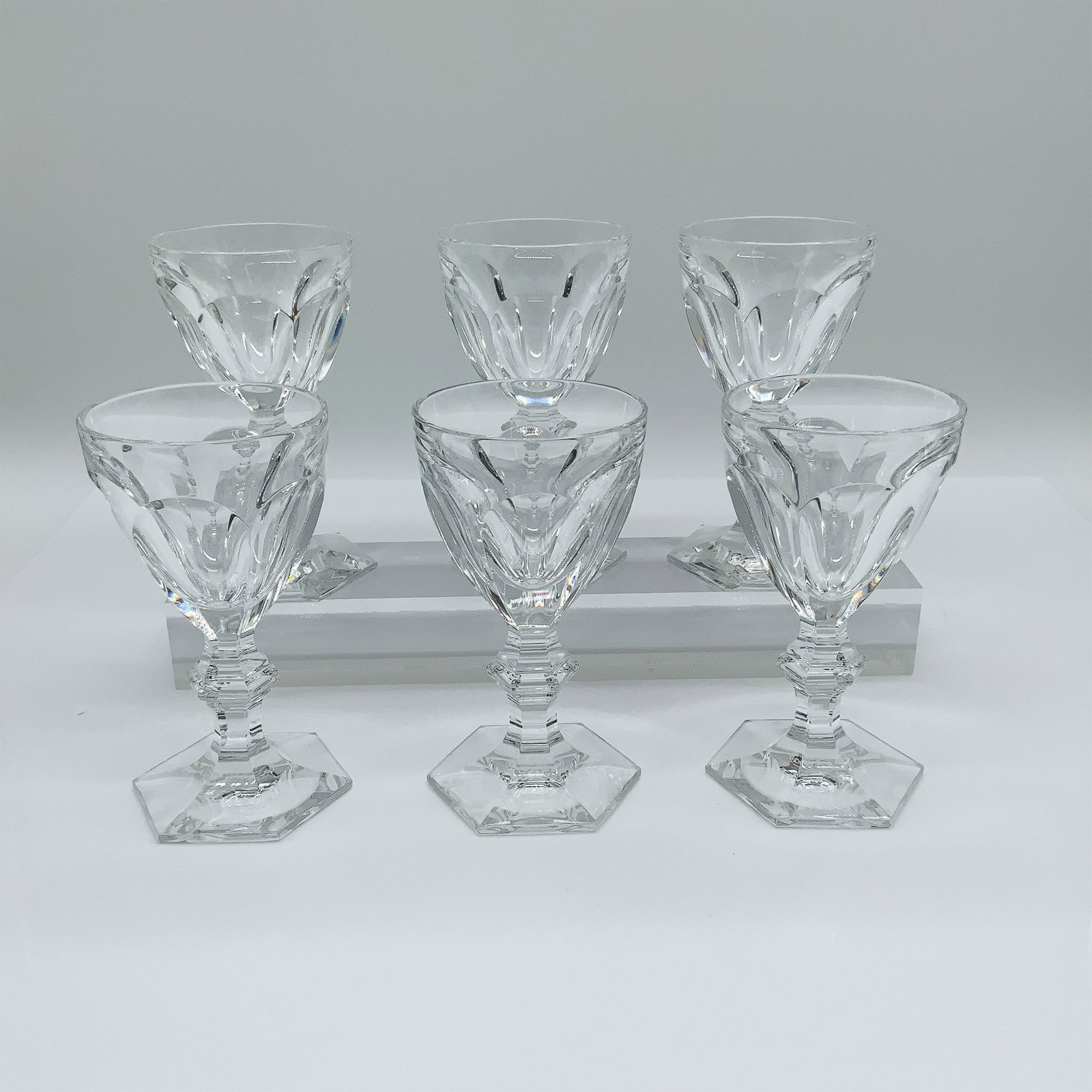 6pc Baccarat Harcourt Crystal Wine Glasses: Set of six Baccarat Harcourt crystal wine glasses, a timeless design introduced in 1841. Featuring faceted bowls, sculpted stems, and hexagonal bases, these glasses reflect Baccarat?s signature brilli