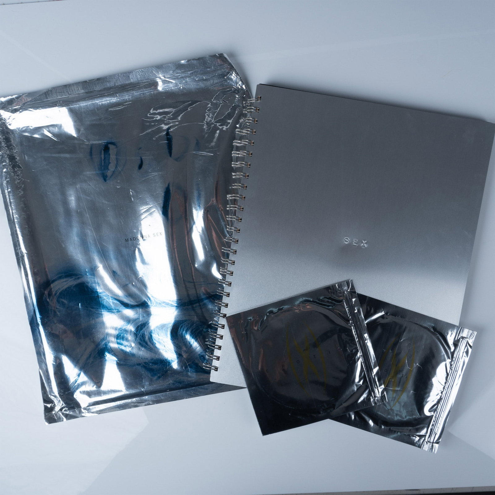 Madonna Sex Book 1st Printing with Foil Cover & CD: Madonna aluminum covered Sex book with original metal foil jacket & sealed CD. 1992 1st Printing. Published by Warner Books, the book features adult content, including softcore pornography and simulat