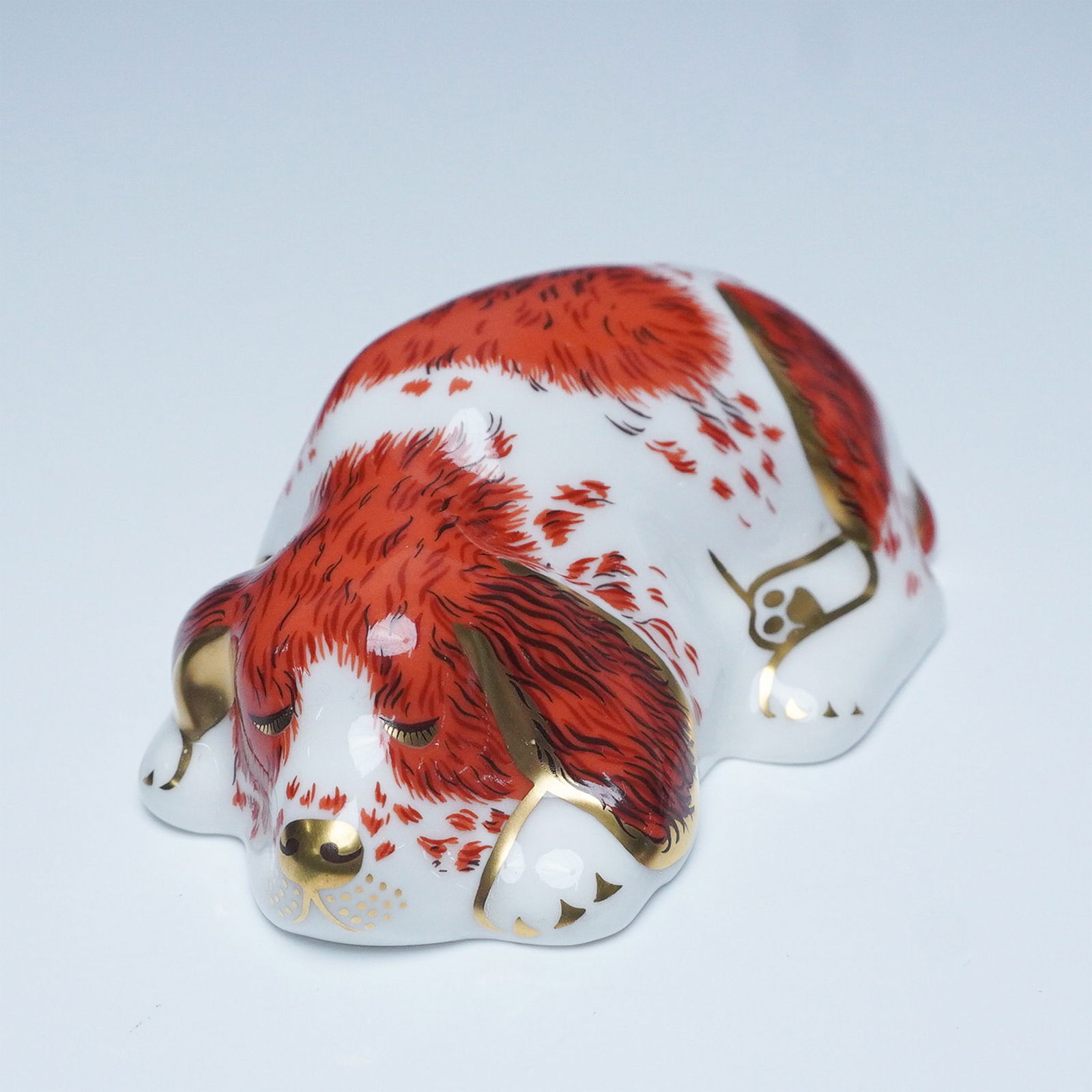 Royal Crown Derby Paperweight Puppy Figurine: Charming Royal Crown Derby paperweight figurine depicting a sleeping puppy, finely crafted in bone china with intricate hand-painted red and white fur details accented in 22-karat gold. This collectib