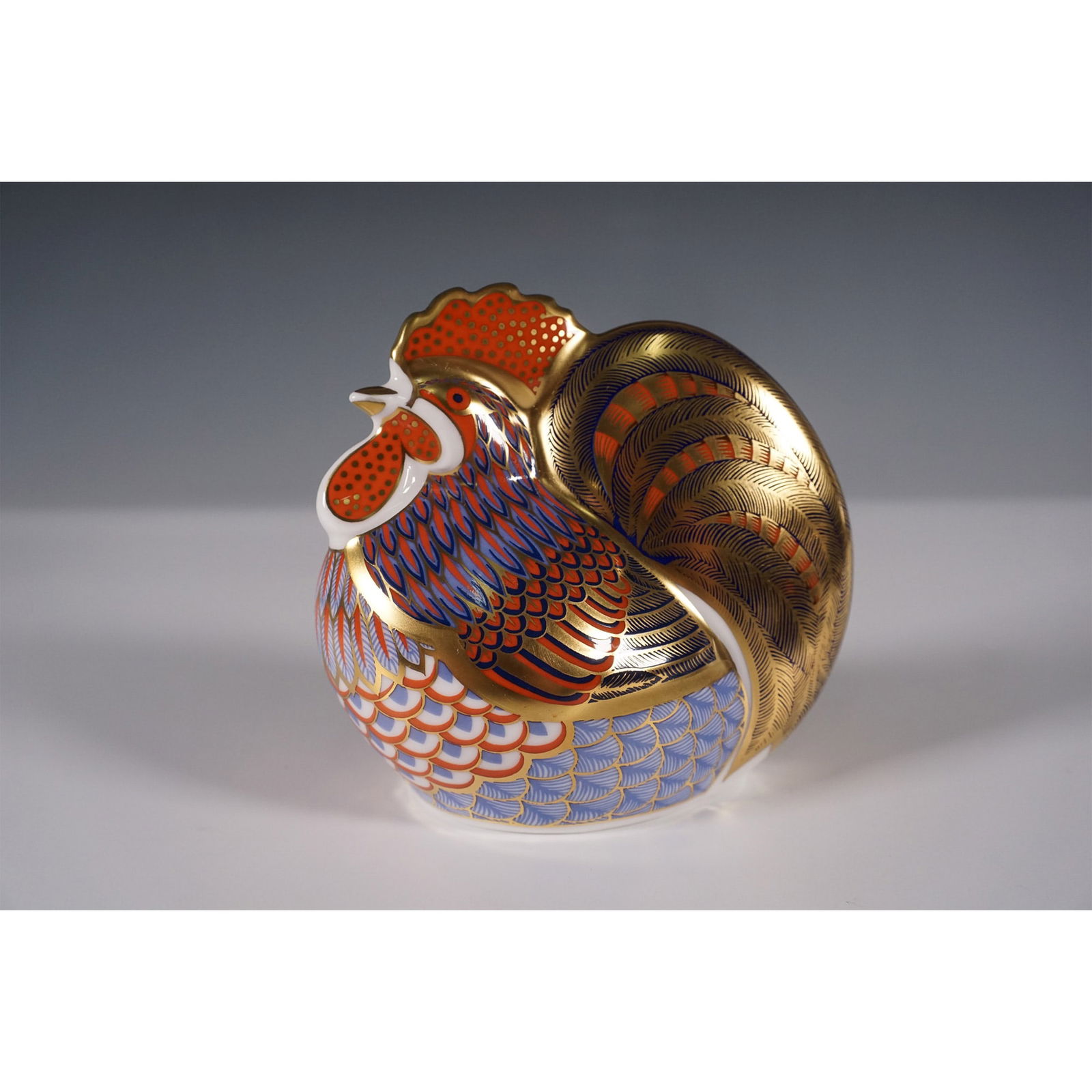 Royal Crown Derby Paperweight, Cockerel: A porcelain rooster paperweight. A fine example of English craftsmanship, featuring intricate hand-applied Imari-style patterns with rich cobalt blue, vibrant orange, and gilt accents. This collectibl