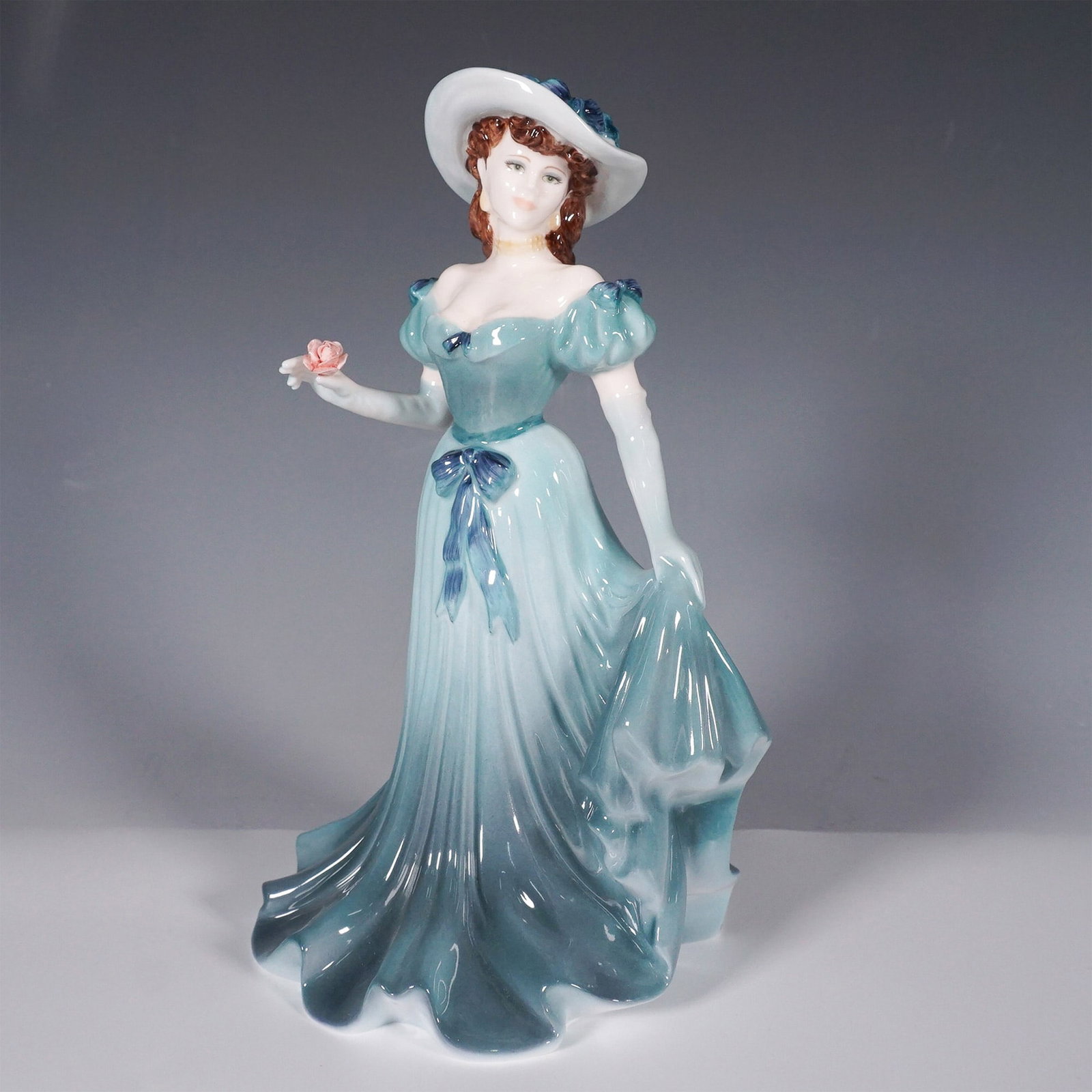 Coalport Bone China Figurine, Christina: Coalport bone china figurine titled Christina from The Collingwood Collection. This elegant hand-decorated figurine depicts a Victorian-era woman in a flowing blue-green gown, adorned with delicate fl