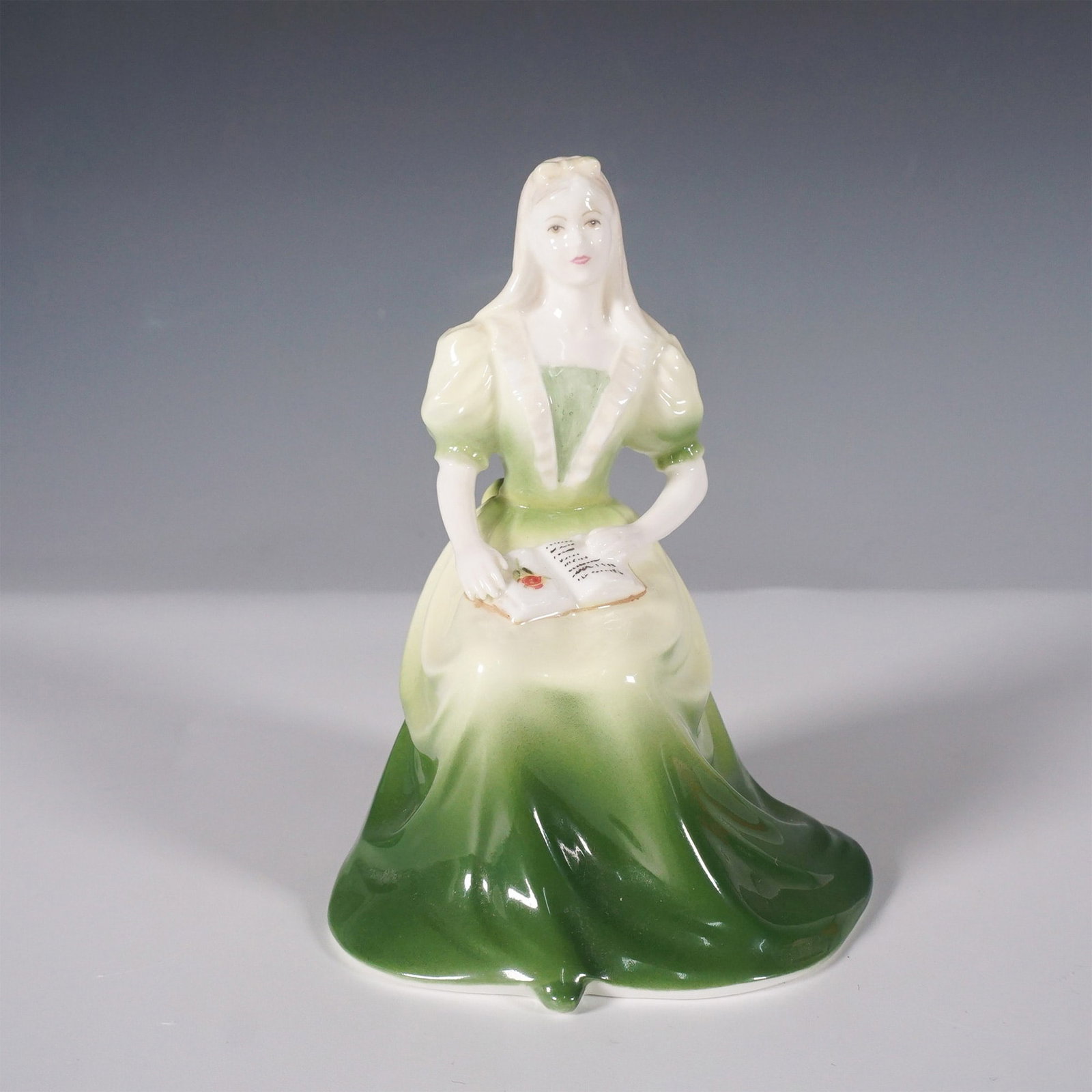 Coalport Fine Bone China Figurine, Lorna: Elegant 4.5-inch Lorna figurine by Coalport, modeled by John Bromley and hand-decorated in fine bone china. This piece portrays a seated young woman in a flowing green gown, delicately holding an open