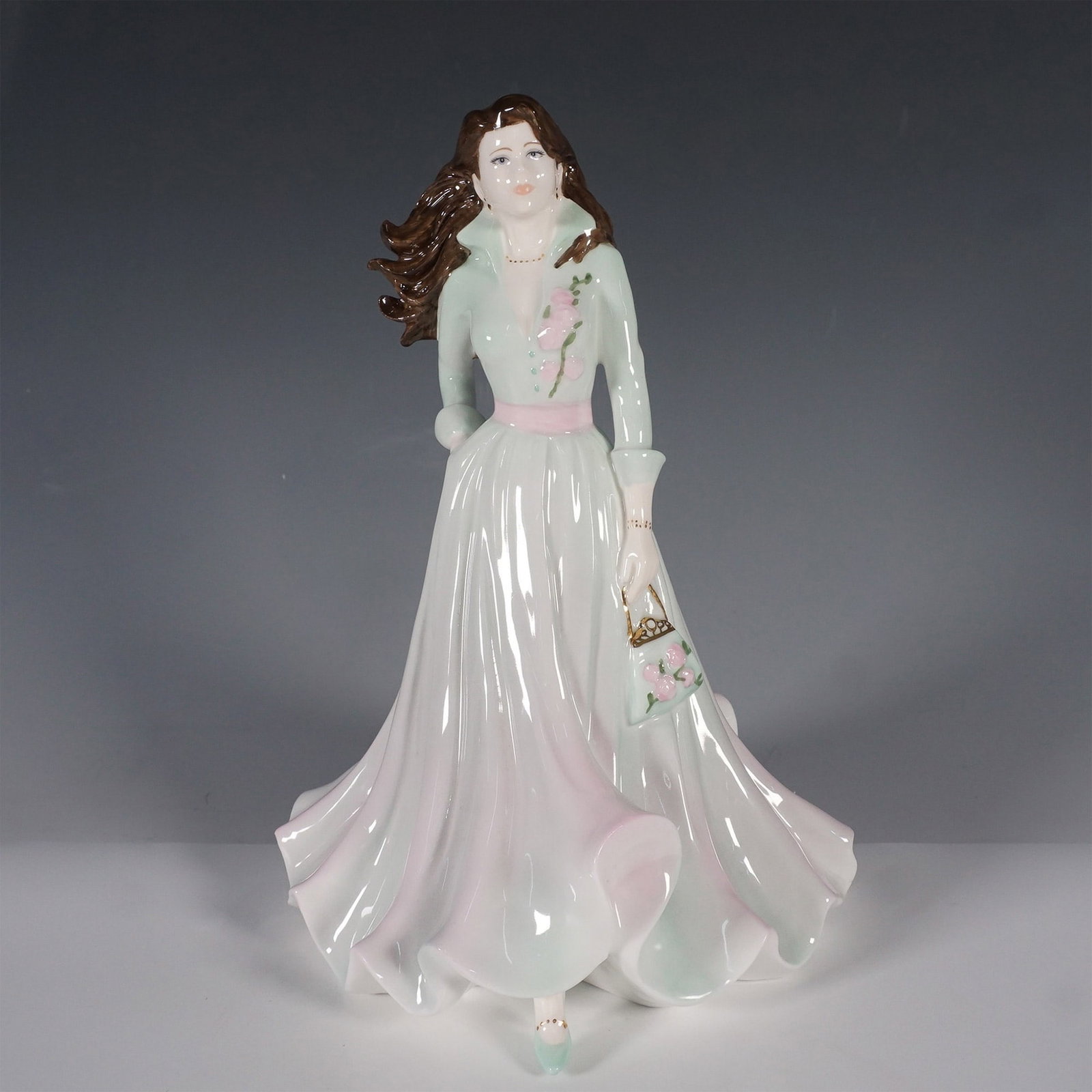 Coalport Ladies of Fashion Figurine, Sarah: A beautifully crafted porcelain figurine from the esteemed Coalport Ladies of Fashion collection, this piece captures the grace and movement of a refined lady in a flowing green pastel gown. Designed 