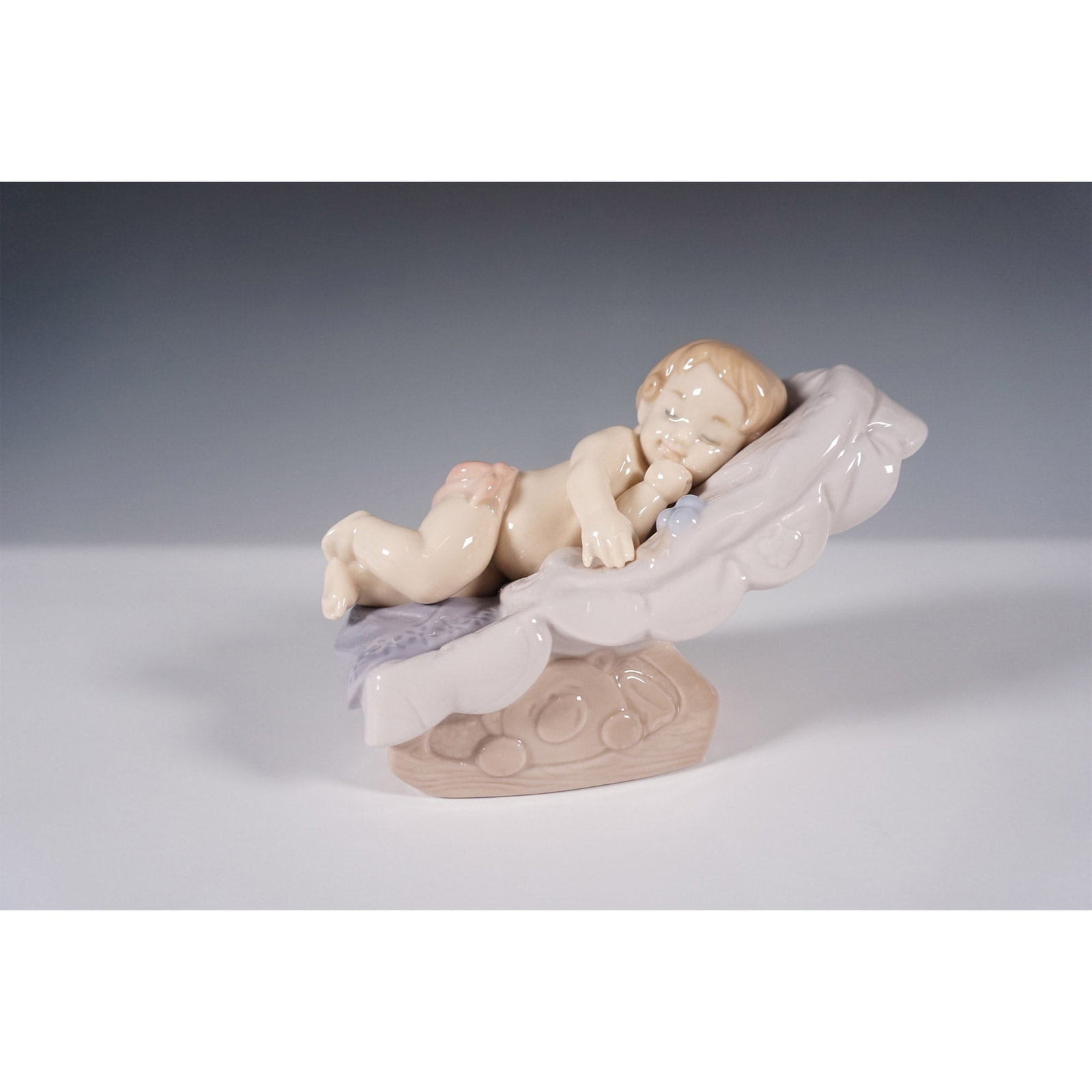 Nao by Lladro Porcelain Figurine "Dream Little Girl" 1609: Charming Nao by Lladro porcelain figurine titled Sleepy Baby in Shell, model number 1609. This delicate handcrafted piece captures a peacefully sleeping baby nestled in a large shell, resting atop a t