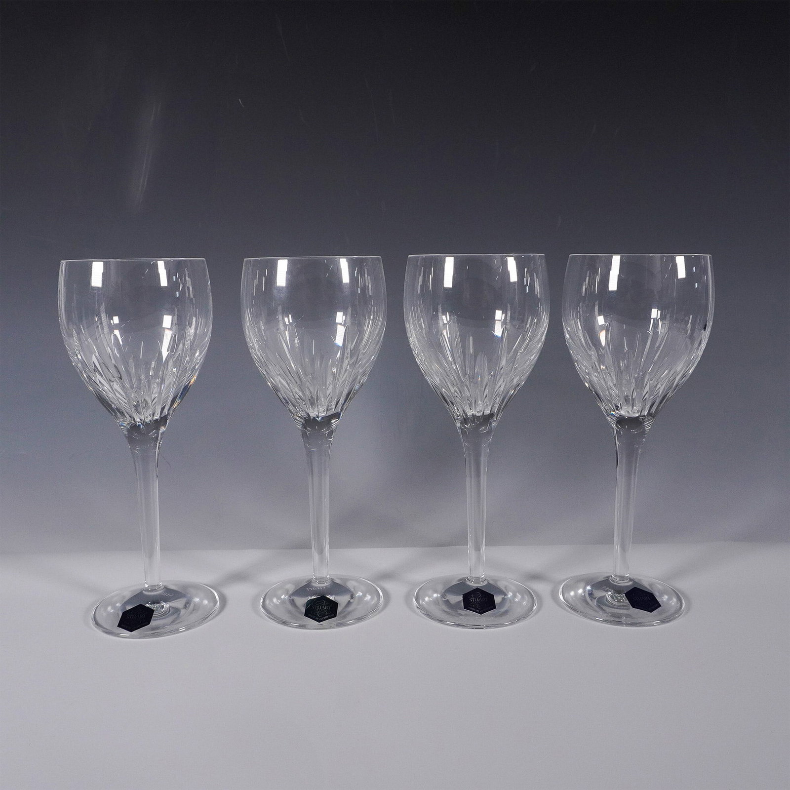 Stuart Crystal Beginnings Wine Glasses, Set of 4: This set of four elegant wine glasses from Stuart Crystal's Beginnings collection showcases the brand's renowned craftsmanship. Each glass features intricate cut patterns that enhance the brilliance a