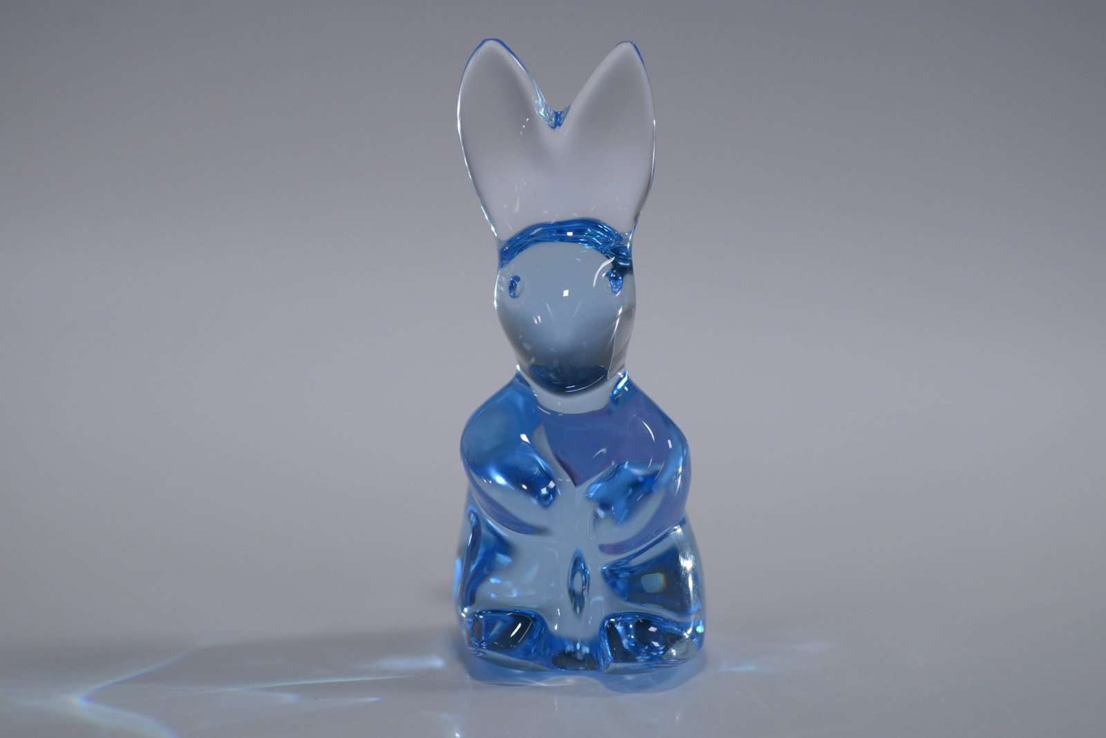 Baccarat Crystal Blue Rabbit Figurine: Chic Baccarat crystal rabbit figurine in vibrant blue, showcasing exceptional craftsmanship with a smooth, reflective surface and intricate detailing. The piece features the original Baccarat sticker,