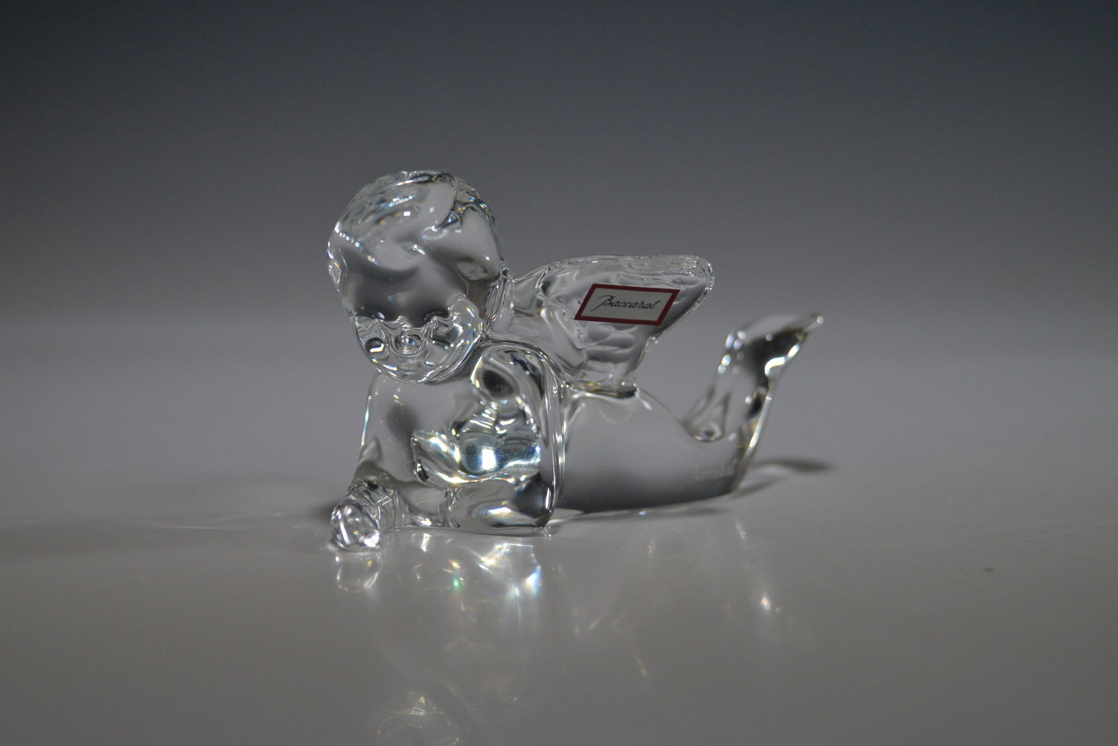Baccarat Crystal Angel Figurine: A beautiful Baccarat crystal figurine depicting an angel lying down in a relaxed position with elegantly crafted wings. The piece features the Baccarat France acid-etched mark and retains its original