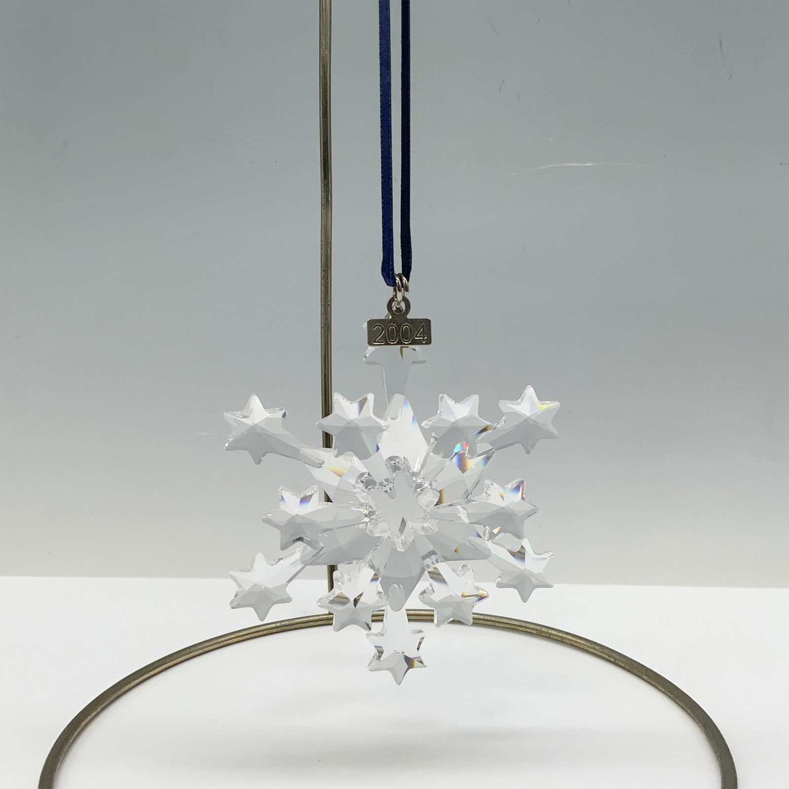 Swarovski Crystal 2004 Christmas Ornament: Limited edition Swarovski Christmas ornament with 12 points consisting of 6 stars and 6 shooting stars as well as a metal tag with 2004 etched on it. Hung by a blue ribbon. Swarovski backstamp 631562.