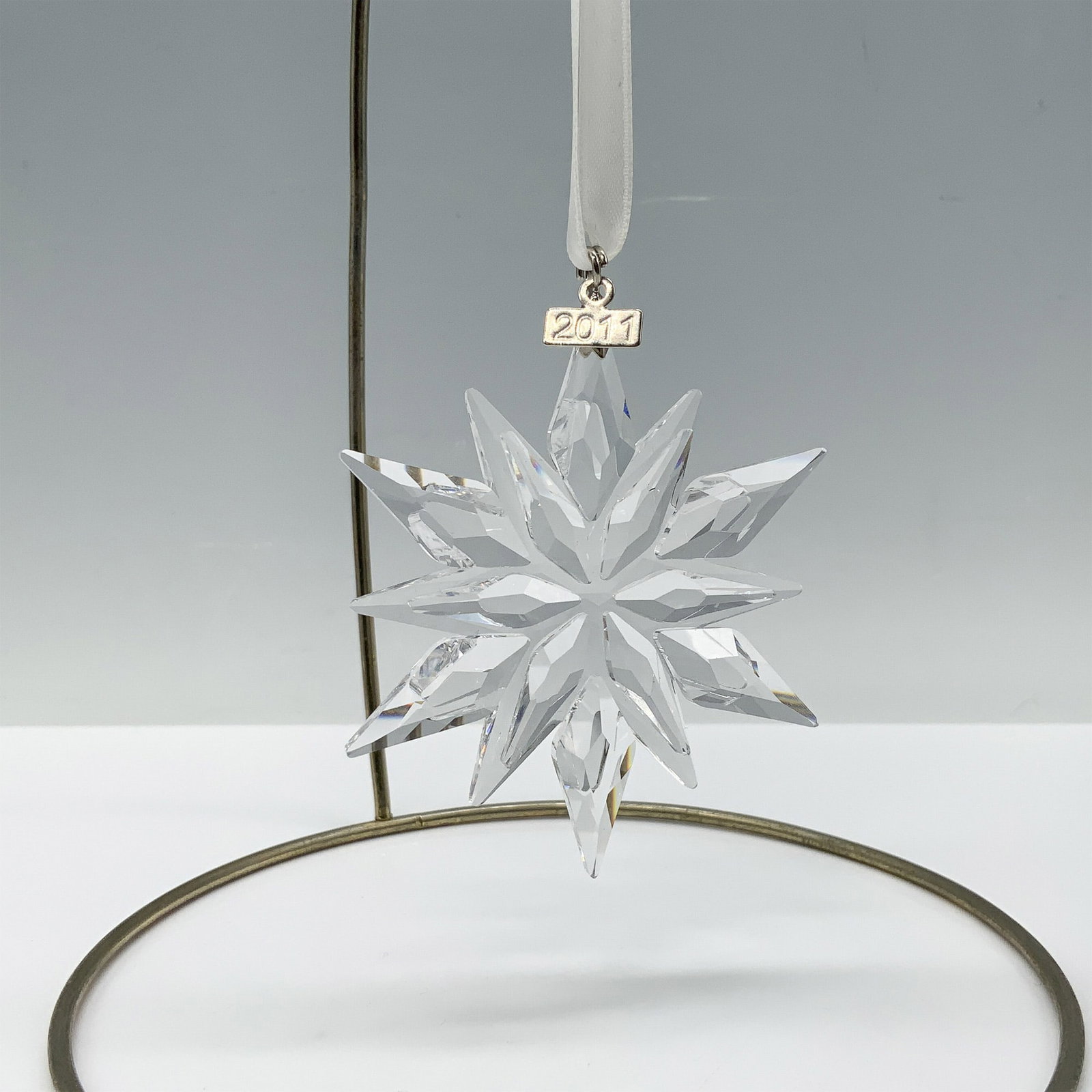 Swarovski Crystal 2011 Christmas Ornament: Limited edition Swarovski Christmas ornament with 6 outer points and 6 inner points as well as a metal tag with 2011 etched on it. Hung by a white satin ribbon. Swarovski backstamp 1092037. Artist: Ke