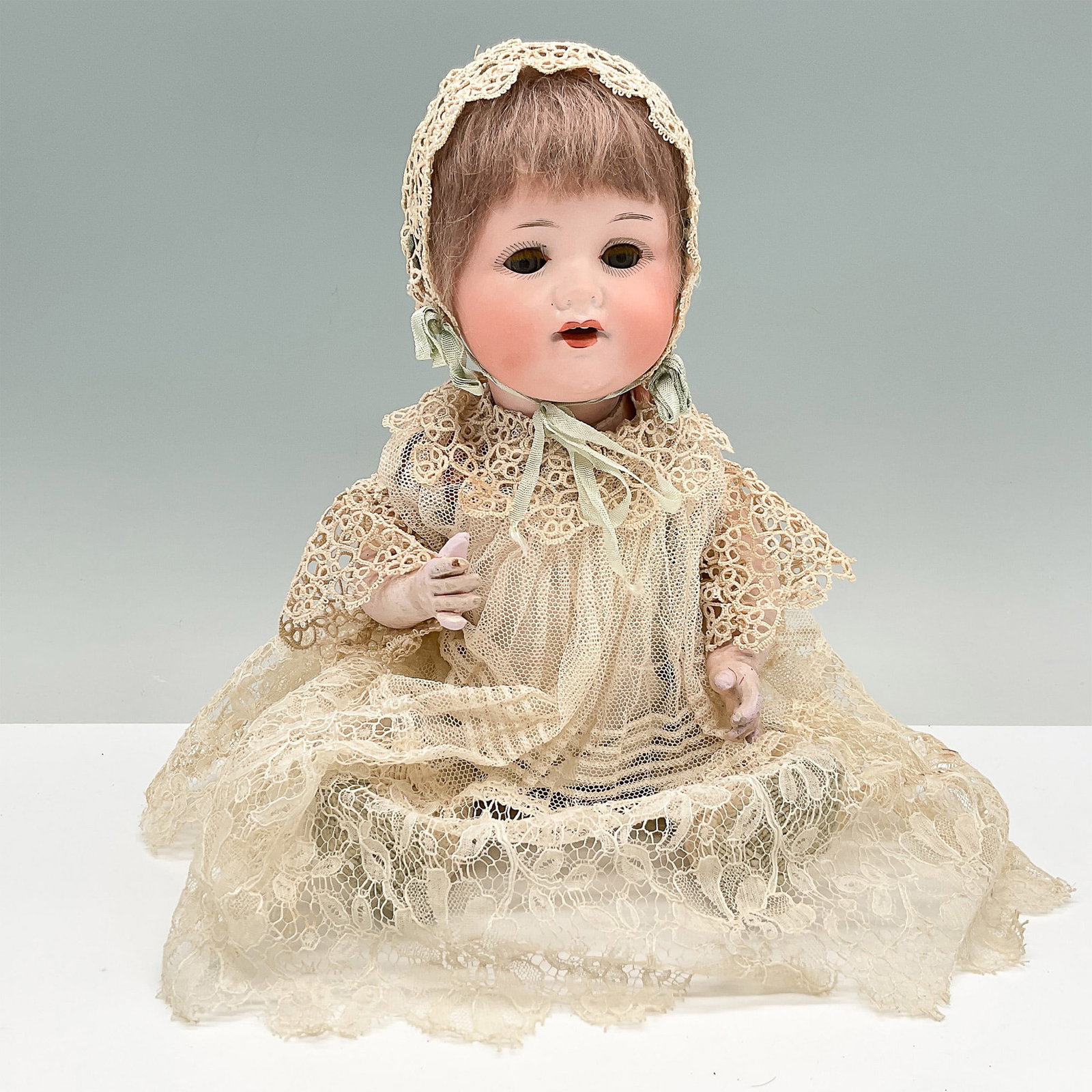 Antique Bruno Schmidt Bisque Baby Doll: Antique German bisque baby doll by Bruno Schmidt, a renowned doll manufacturer from the early 19th century. This charming doll features a delicately painted bisque head with an open mouth, revealing t