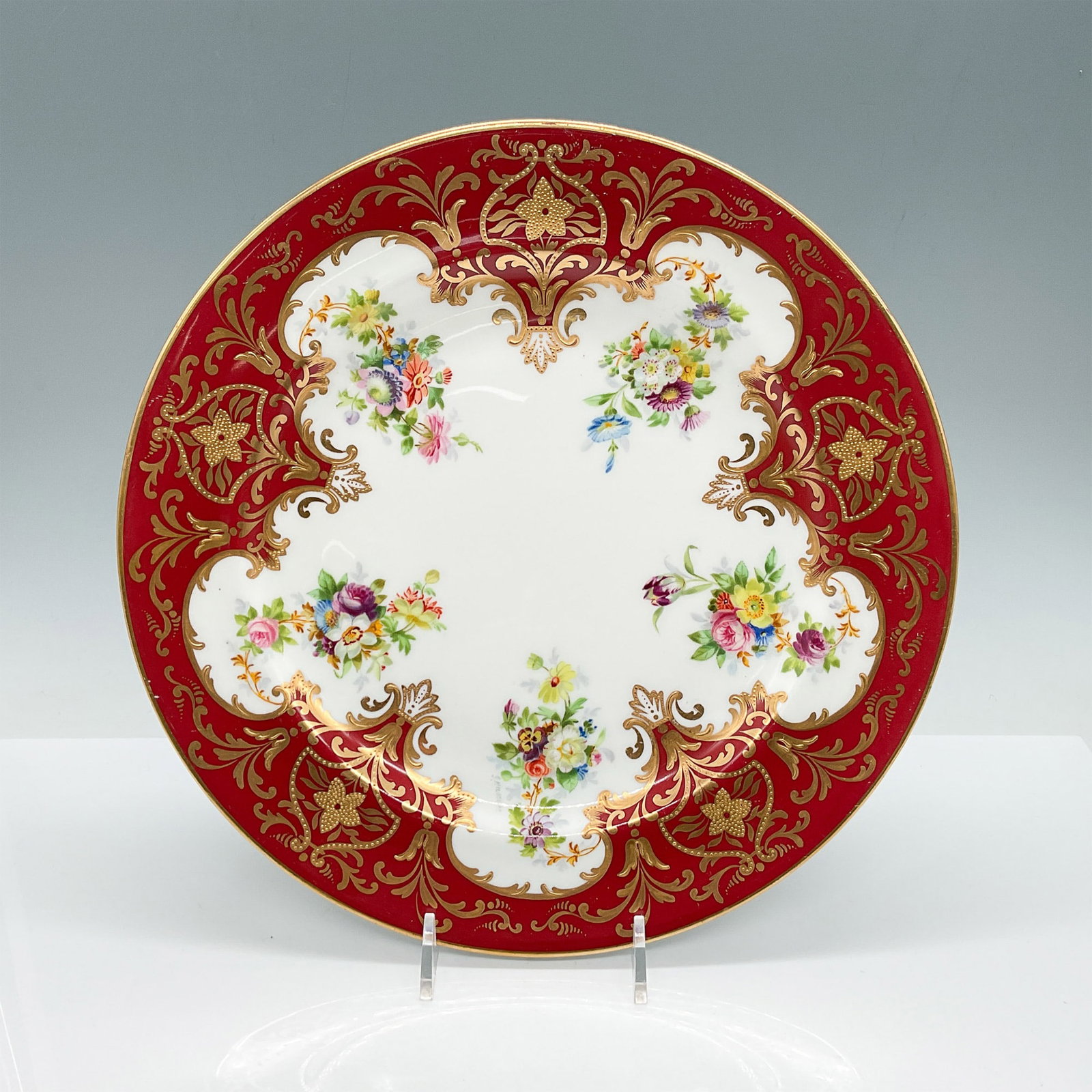 Wedgwood Porcelain Plate Signed J. Haskell: An exquisite Wedgwood porcelain plate featuring a lavish red and gold border with intricate gilt detailing, framing vibrant floral bouquets. The plate is hand-painted and signed by artist J. Haskell, 