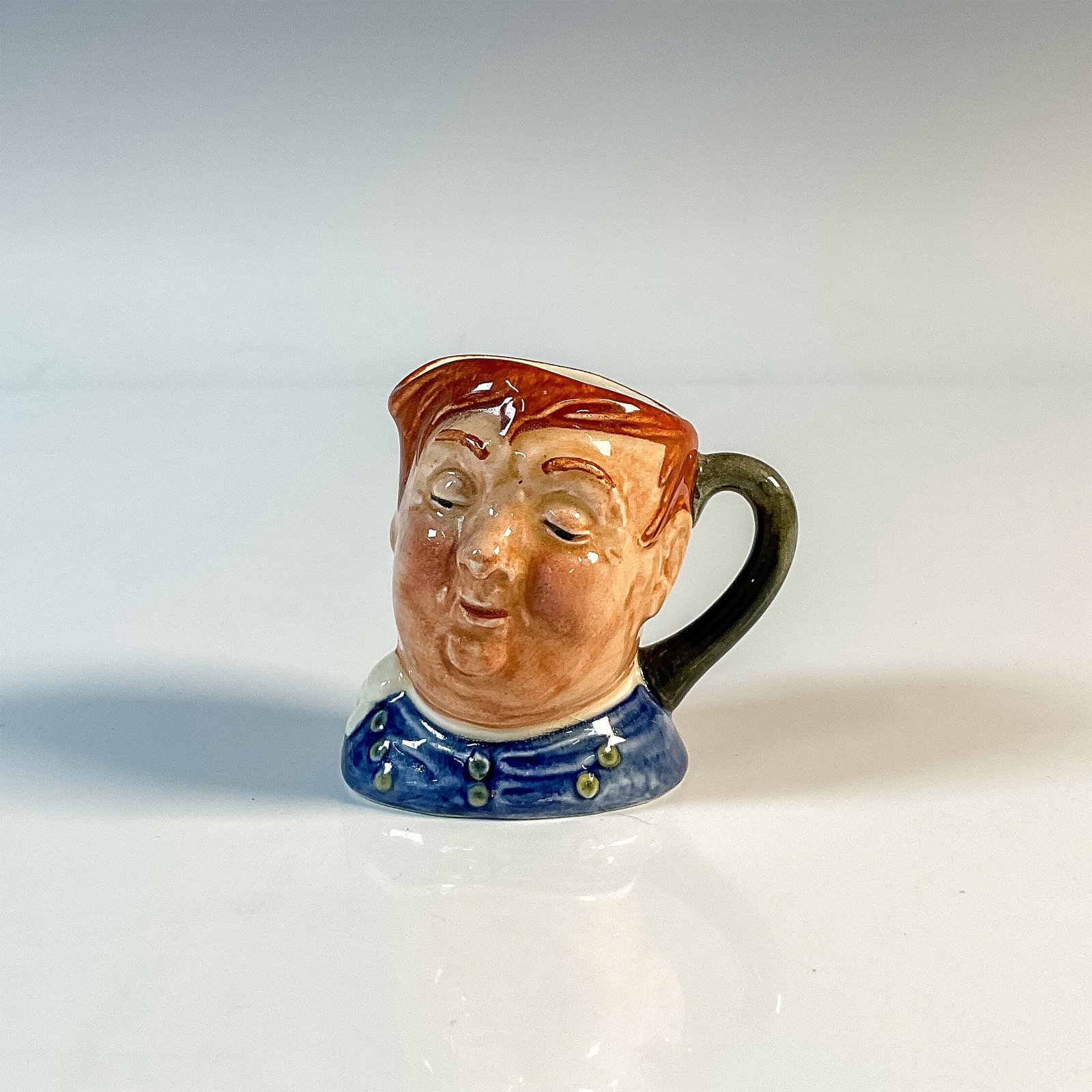 Fat Boy D6139 - Mini - Royal Doulton Character Jug: Blue shirt; white scarf. Royal Doulton backstamp. Artist: Leslie Harradine and Harry Fenton Issued: 1940 - 1960 Dimensions: 2.5"H Country of Origin: England