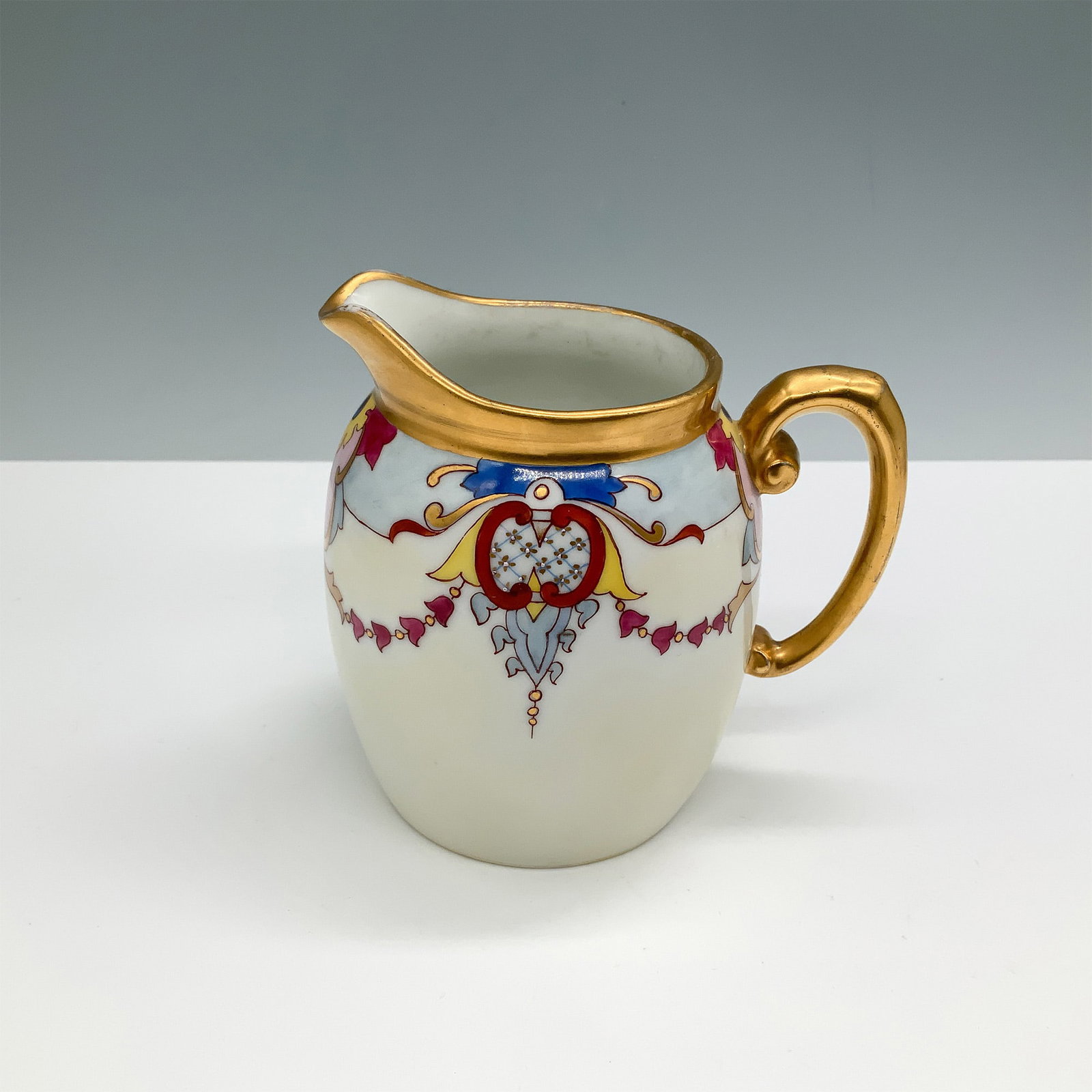 T&V Limoges Hand-Painted Creamer, Art Nouveau Style: A beautiful T&V Limoges hand-painted porcelain creamer featuring a delicate Art Nouveau-style design with ornate motifs, heart-shaped accents, and vibrant pink and blue highlights. The piece is enhanc
