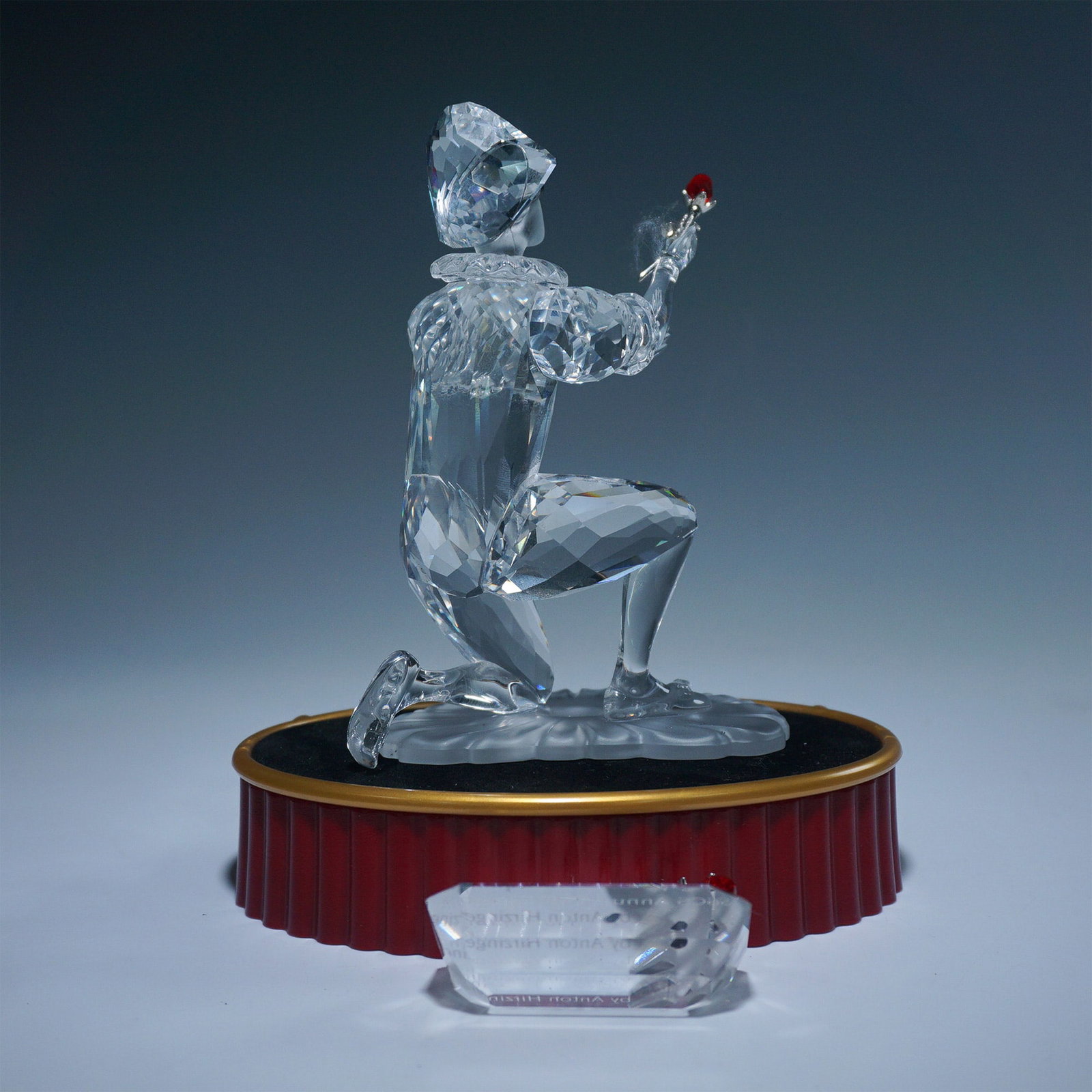 3pc Swarovski Crystal Figurine, Harlequin with Base and Plaque: This Swarovski Harlequin figurine is a dazzling representation of the iconic masked performer and is part of the prestigious Swarovski Masquerade collection. Expertly crafted in clear faceted crystal,