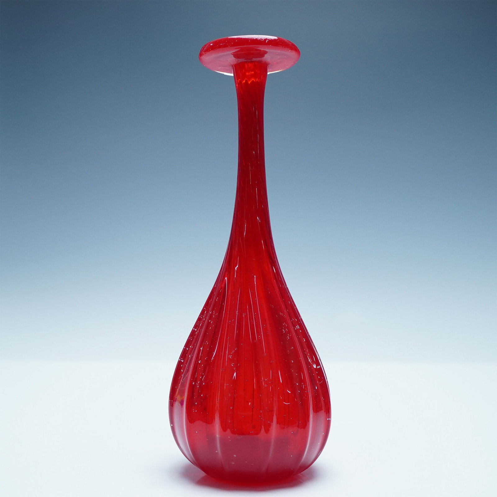 Vintage Red Glass Table Vase: Striking red glass vase featuring a unique twisted design with trapped air bubbles, showcasing the artistry of blown glass craftsmanship. The vase exhibits a ribbed texture along the body, enhancing i