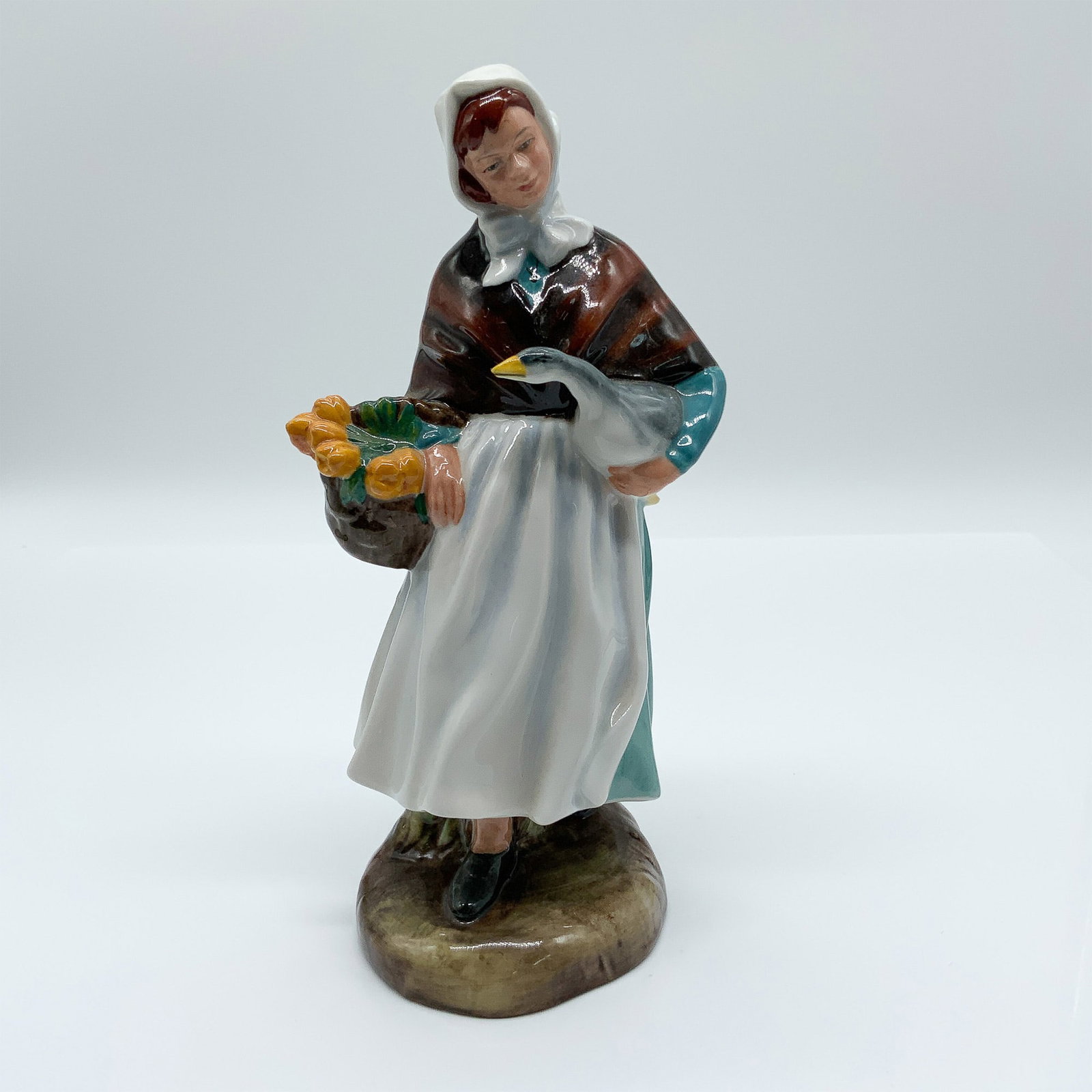 Royal Doulton Porcelain Figurine, Country Lass HN1991: Delightful Royal Doulton porcelain figurine titled "Country Lass," model HN1991, designed by Leslie Harradine. This figurine depicts a charming country girl holding a goose and a basket of vibrant yel