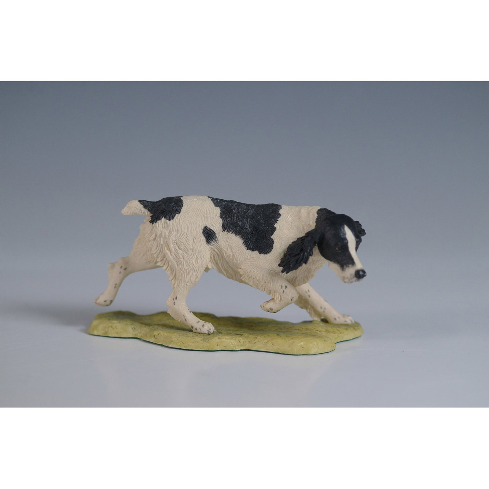 Border Fine Arts Figurine English Springer Spaniel: Border Fine Arts handmade figurine featuring an English Springer Spaniel in a dynamic pointing stance. The black and white spaniel is captured mid-motion, standing atop a textured base. Designed by re