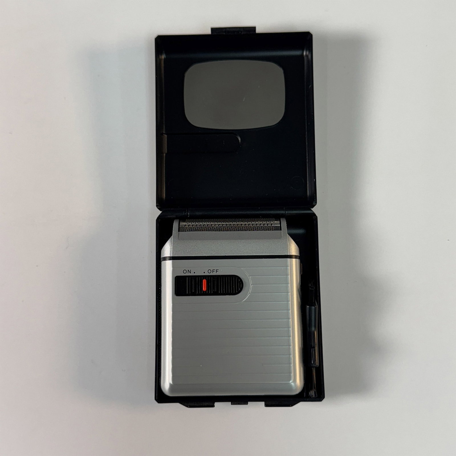 Vintage Toshoku Ltd. Travel Electric Shaver with Case: Compact vintage travel electric shaver by Toshoku Ltd., Japan, featuring a sleek silver-tone body with an on/off switch and foil shaving head. The shaver operates on DC 3V and includes its original ha