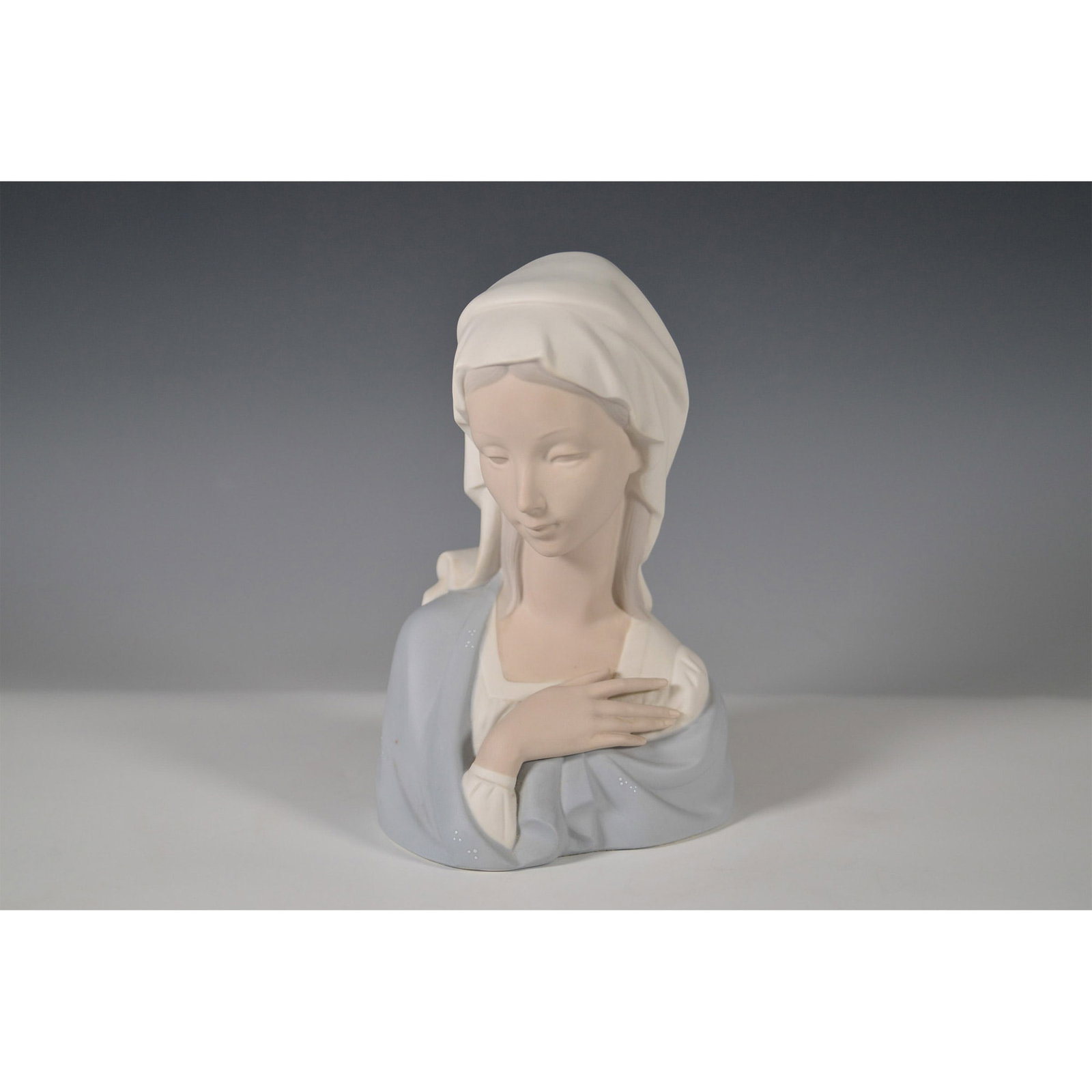 Lladro Porcelain Bust, Madonna Head 1014649: Presenting a serene Lladro porcelain bust, model 1014649, titled Madonna Head. This exquisite piece, designed by artist Vicente Martinez, was issued in 1969. It features a matte finish and depicts the