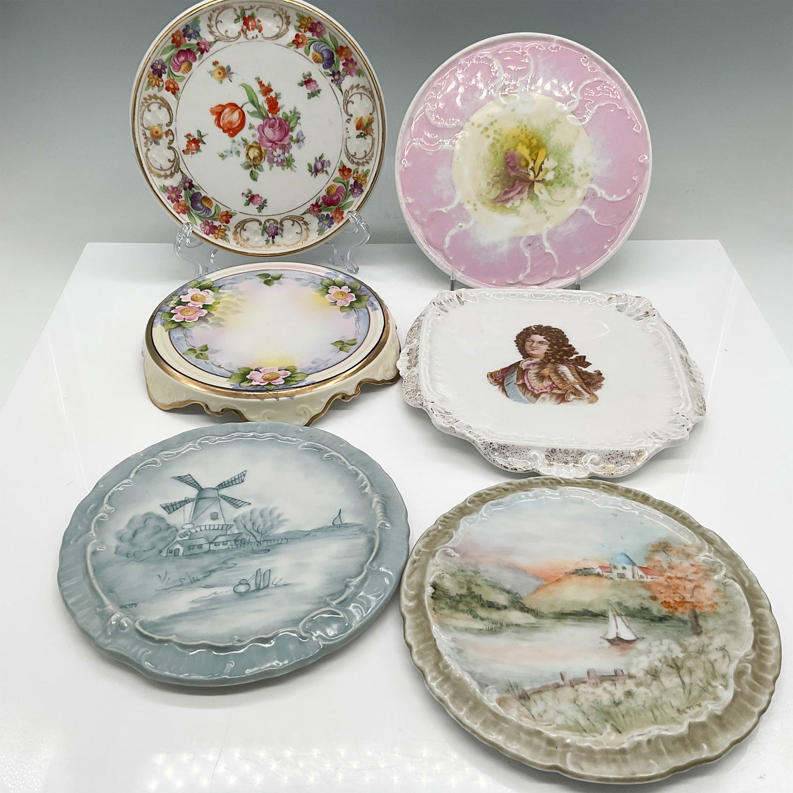 6pc Antique and Vintage Porcelain Trivet Plates Collection: A collection of six antique and vintage porcelain trivet plates ranging from 5" - 7.5" dia., featuring a variety of intricate hand-painted and transfer designs. Each plate is uniquely decorated, inclu
