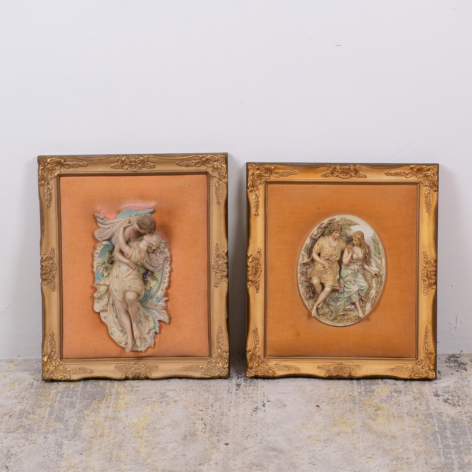 Pair of Capodimonte-Style Porcelain Plaques in Ornate Frames: This lot includes two exquisite Capodimonte-style porcelain relief plaques on velvet mounted in ornate gilded frames, showcasing intricate craftsmanship and romantic themes. Plaque one: Features a ten