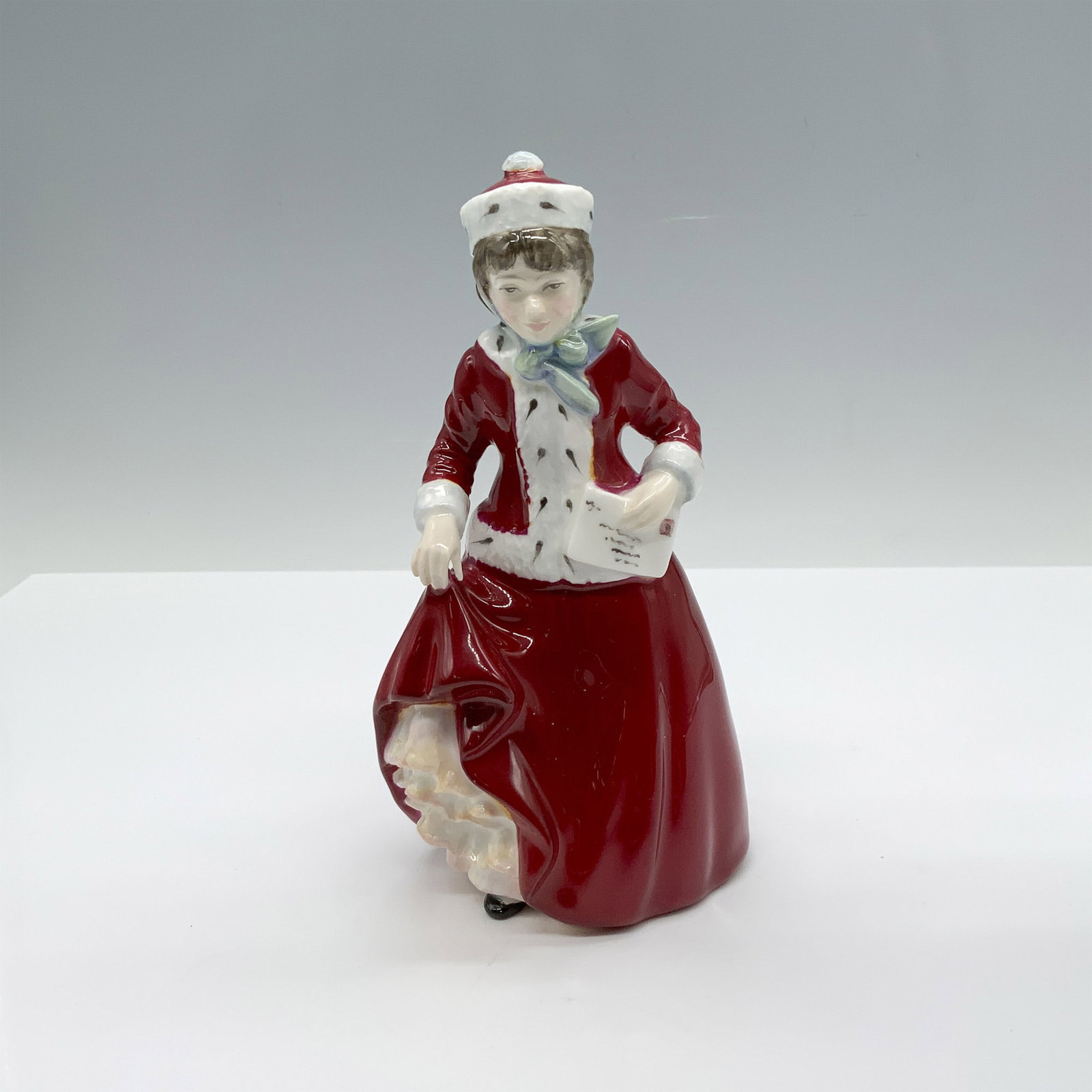 Royal Doulton Bone China Figurine, Best Wishes HN3426: Handmade and hand decorated glossy figure from the Child Study Series that features a girl in winter wear carrying a letter. Royal Doulton backstamp. Artist: Nada Pedley Issued: c. 1993 Dimensions: 3.