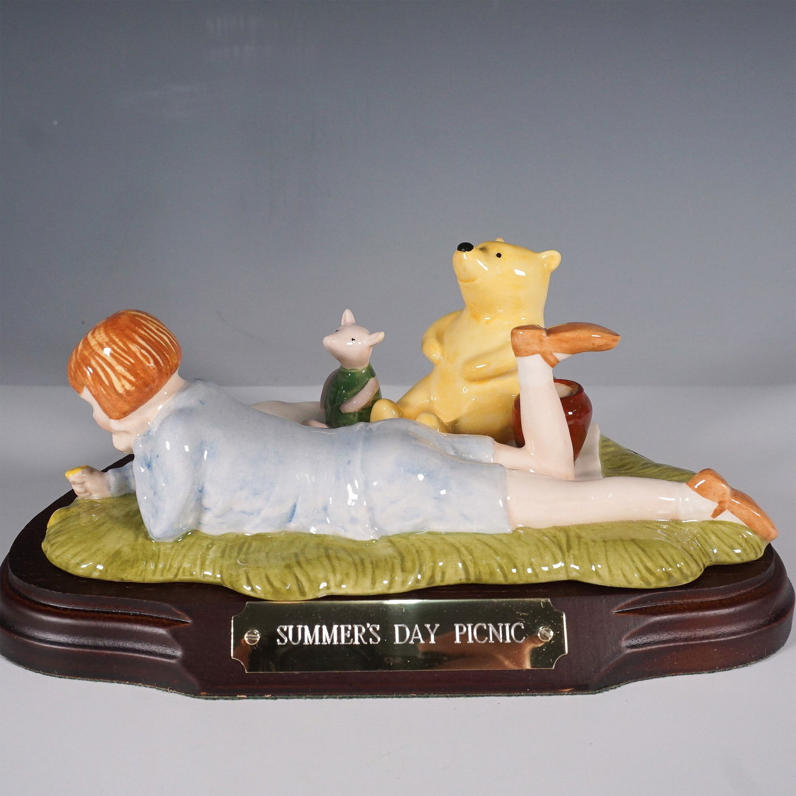 Royal Doulton Winnie-the-Pooh "Summer?s Day Picnic" Figurine: Charming Summer's Day Picnic figurine from Royal Doulton?s Winnie-the-Pooh Collection. Designed by Warren Platt, this hand-painted porcelain piece captures Christopher Robin, Piglet, and Winnie-the-Po