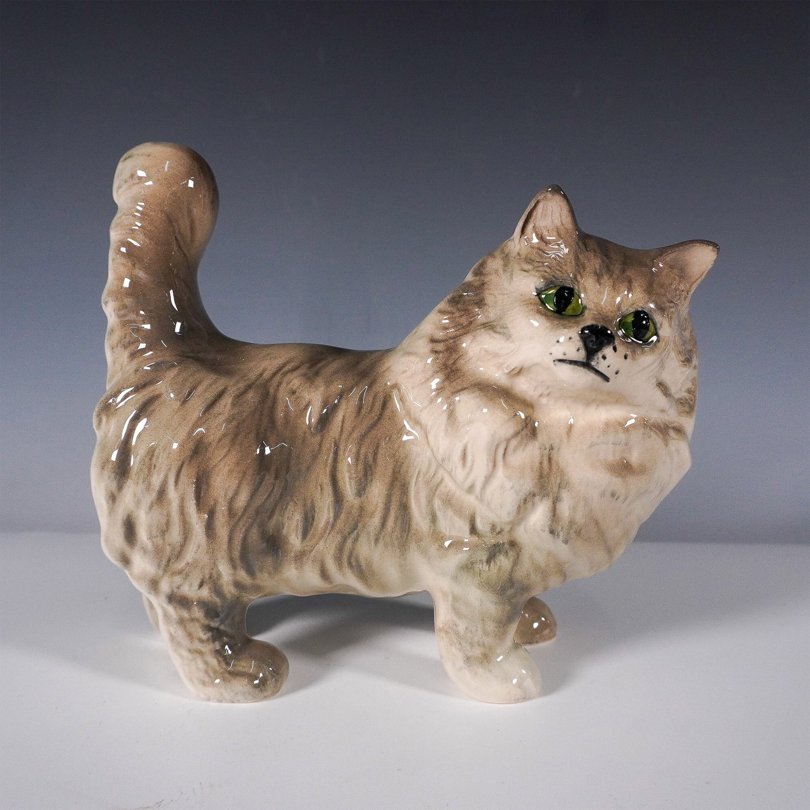 Royal Doulton Persian Cat Grey Figurine DA132: This is a Royal Doulton porcelain figurine depicting a Persian cat. Crafted with fine detail and hand-painted to showcase the lifelike features of the cat's soft fur and expressive face, this figurine