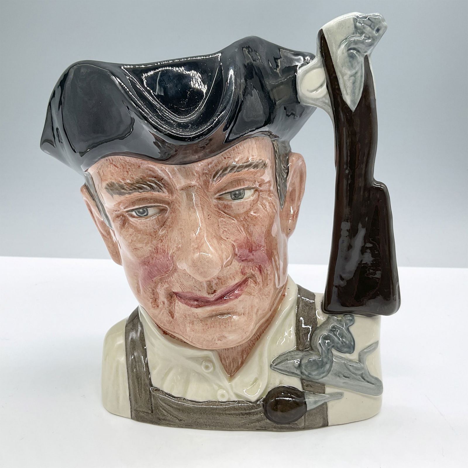 Gunsmith D6573 - Large - Royal Doulton Character Jug: Black hat, cream shirt, light brown apron. Royal Doulton backstamp. Artist: David B. Biggs Issued: 1963 - 1983 Dimensions: 7''L x 5''W x 7.5''H Country of Origin: England
