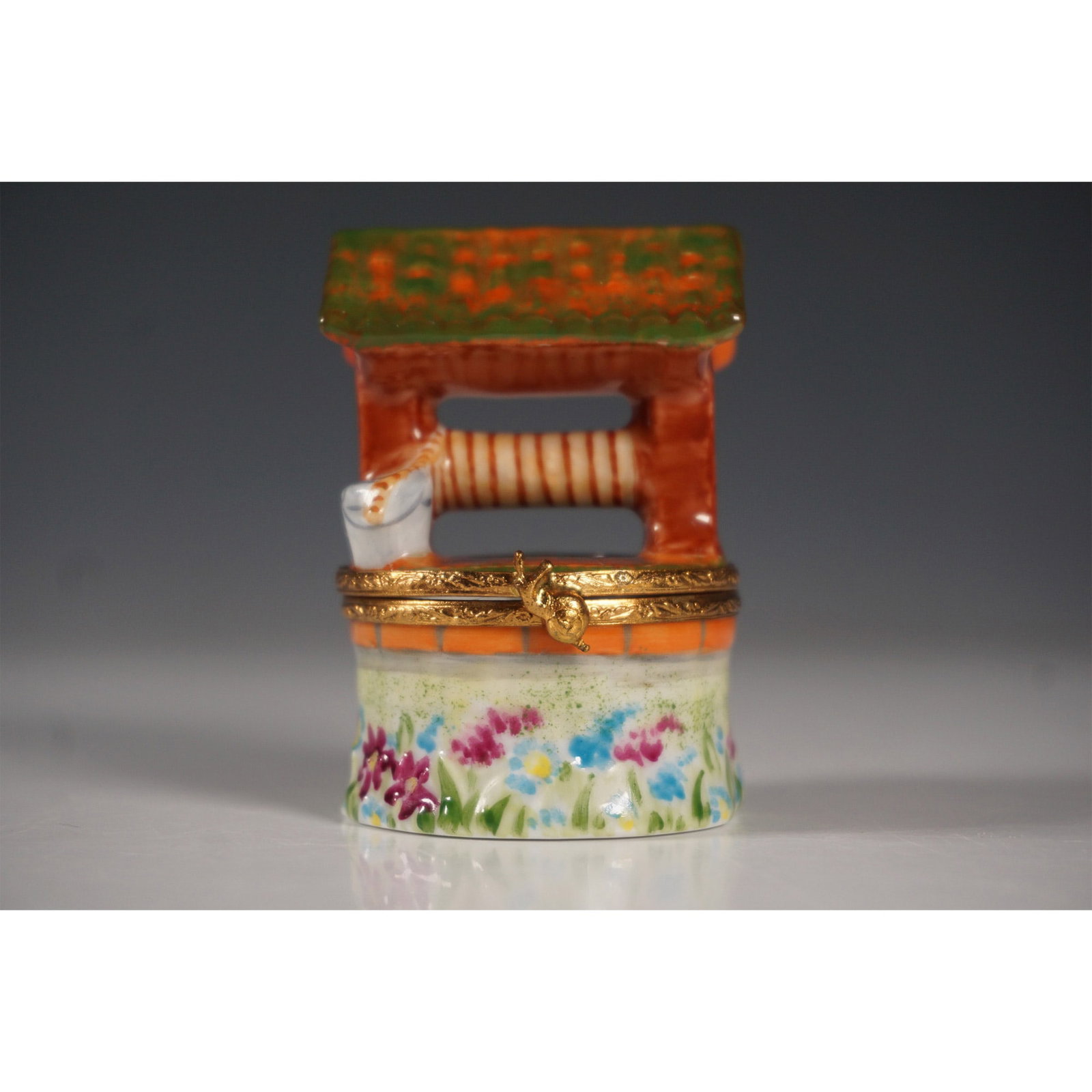 Limoges France Figurine Box, Wishing Well: Exquisite Limoges France hand-painted porcelain figurine box in the shape of a wishing well. This hinged trinket box features a floral base with a brick-style well, a textured green roof, and a small 