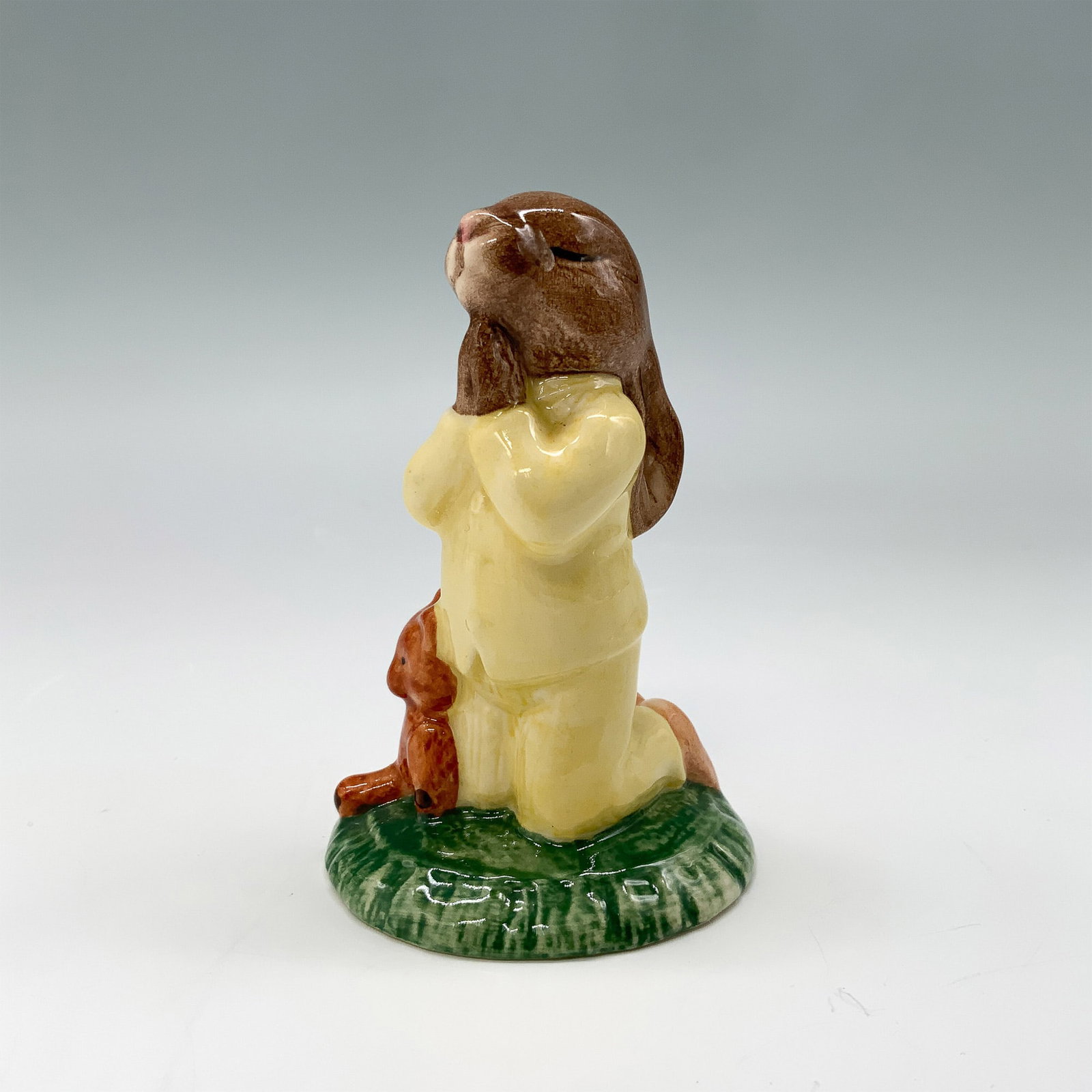 Signed Royal Doulton Bunnykins Figurine, Bedtime DB103: Royal Doulton Bunnykins figurine titled Bedtime, model DB103. This collectible piece features a kneeling bunny in a yellow outfit with a teddy bear, capturing a charming bedtime moment. The figurine i
