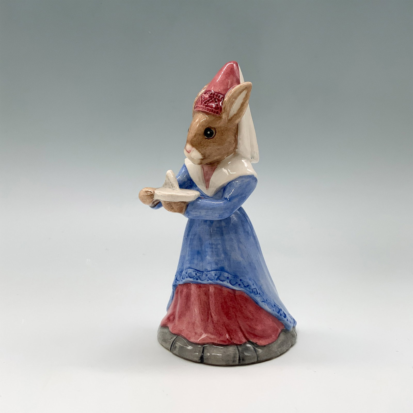 Royal Doulton Bunnykins Figurine Sundial DB213: Royal Doulton Bunnykins figurine titled Sundial Bunnykins model DB213. This charming hand painted porcelain piece features a bunny dressed in medieval attire holding a sundial. Designed by Warren Plat
