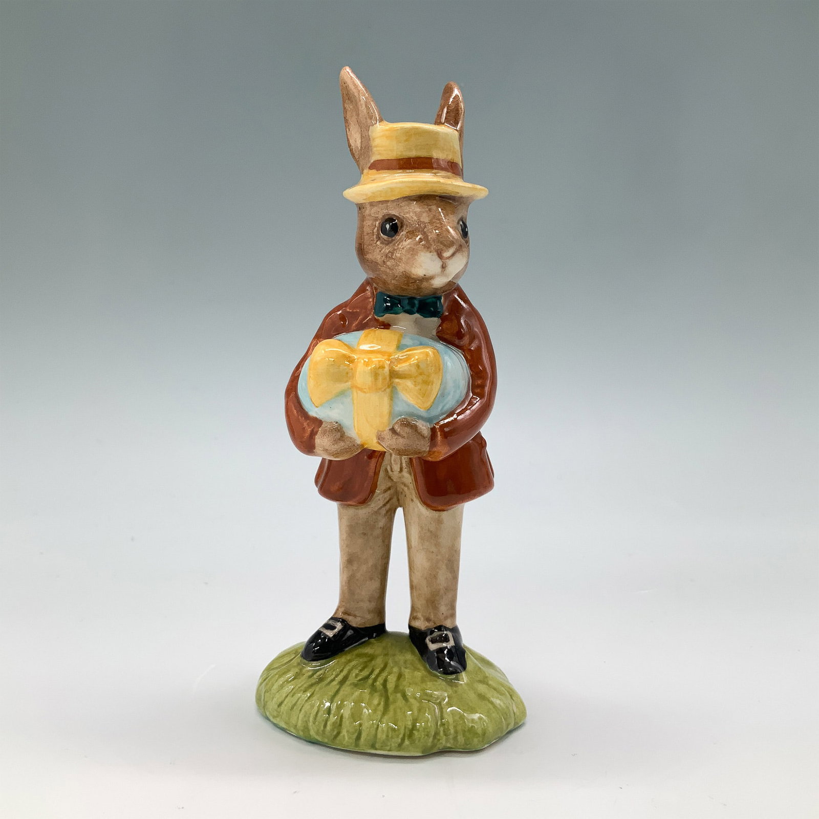 Royal Doulton Bunnykins Figurine, Mr Bunnykins DB18 w/ Box: Royal Doulton Bunnykins figurine titled Mr Bunnykins, At The Easter Parade, DB18. Made of fine bone china, this charming figurine depicts a rabbit dressed in a brown coat, yellow hat, and blue bow tie