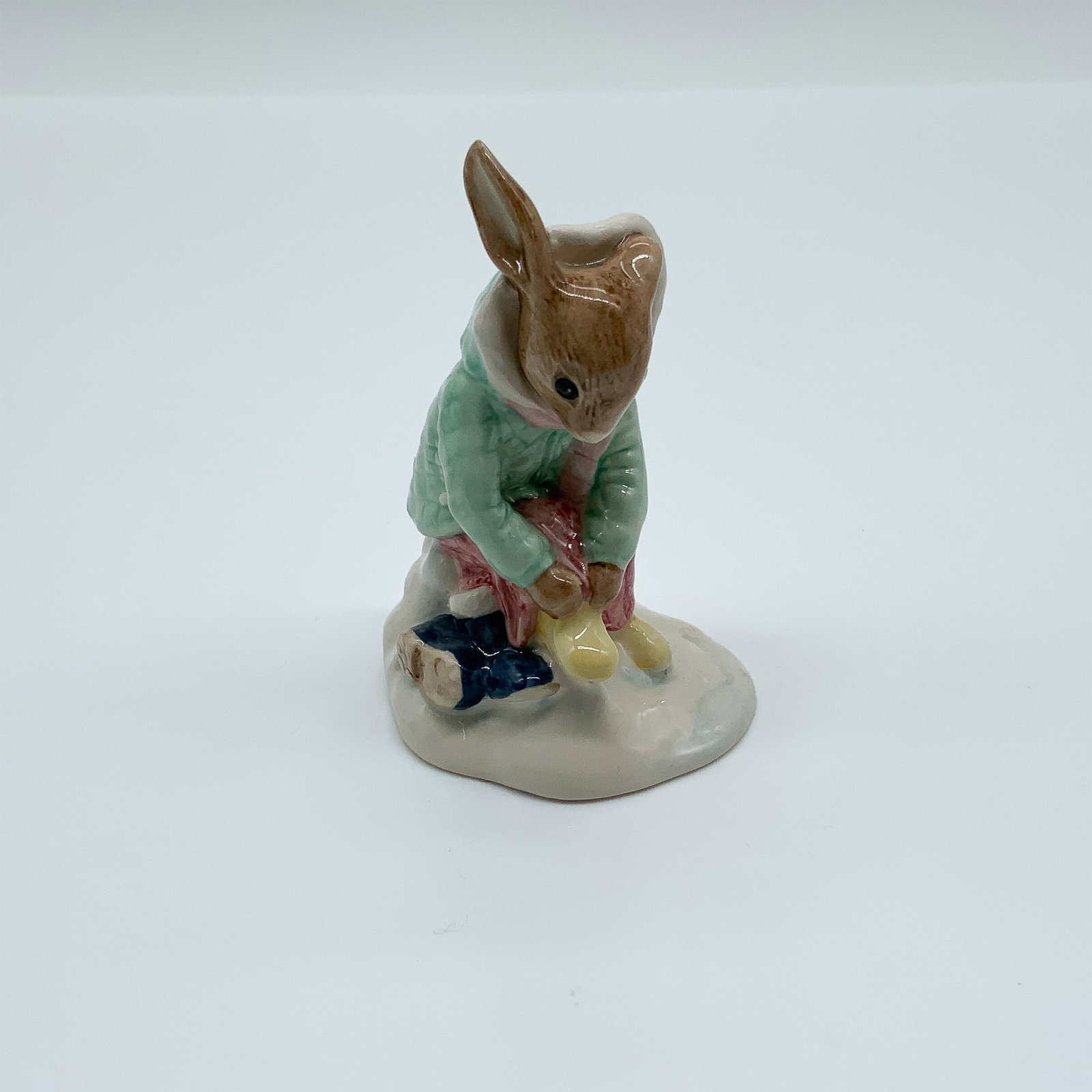 Royal Doulton Bunnykins Figurine, Girl Skater DB153, Signed: This charming Royal Doulton Bunnykins figurine, titled "Girl Skater" (DB153), features a delightful hand-painted design of a young rabbit dressed in winter attire, tying her skates. Created in fine ce