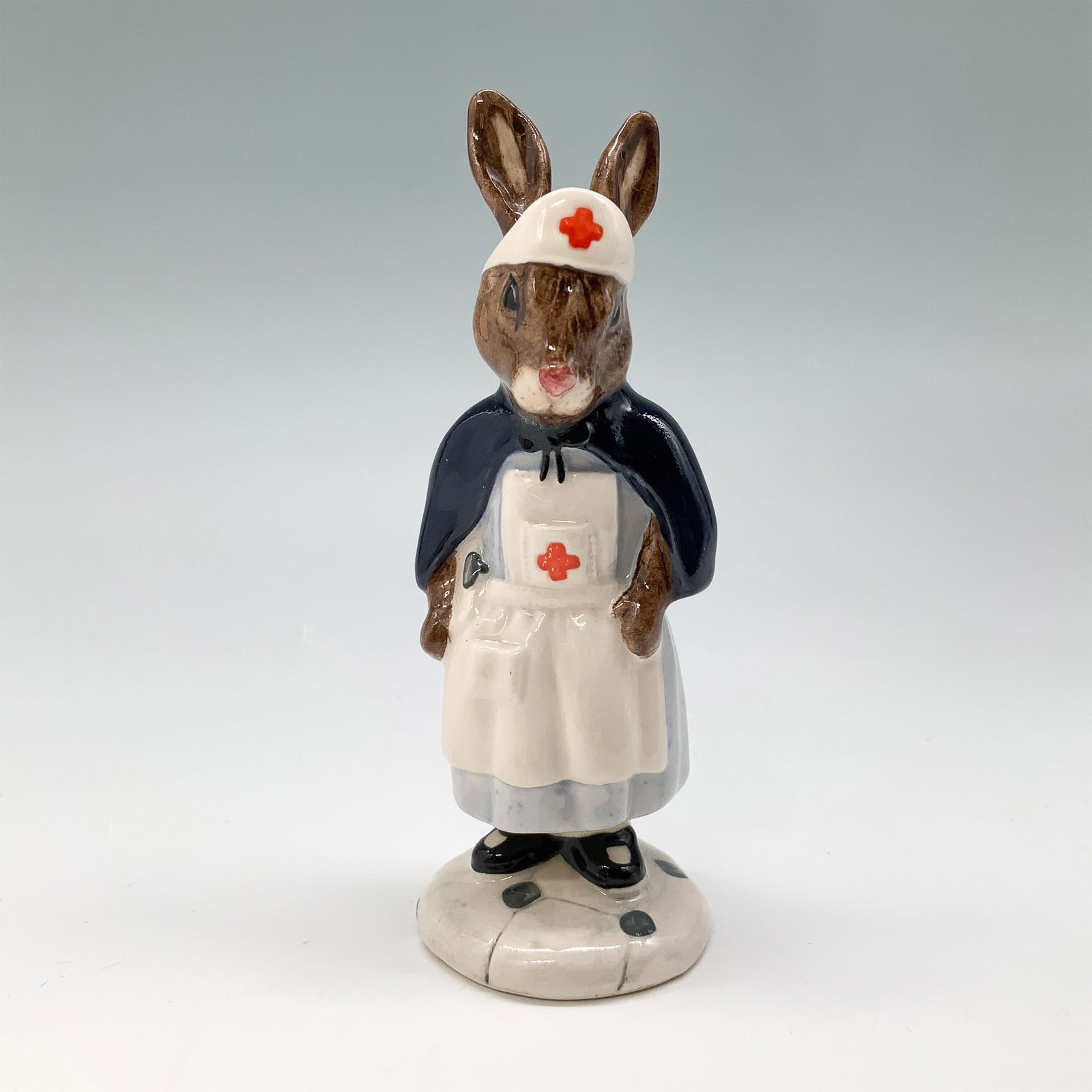 Royal Doulton Bunnykins Figurine, Nurse DB74 w/ Box: Royal Doulton Bunnykins fine bone china figurine, Nurse (DB74), designed by Royal Doulton in 1988. The figurine features a charming nurse bunny dressed in a traditional nurses uniform with a cape and 