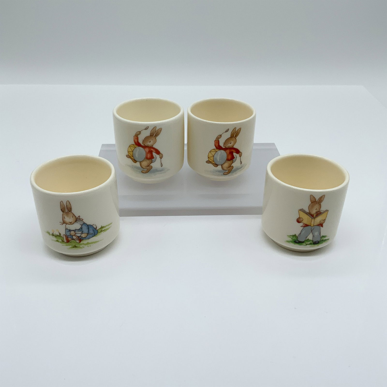 Royal Doulton Bunnykins, 4-Piece Egg Cup Set: This delightful set of four Royal Doulton Bunnykins egg cups features hand-painted scenes of the iconic Bunnykins characters, each in a different whimsical pose. The designs capture the playful charm