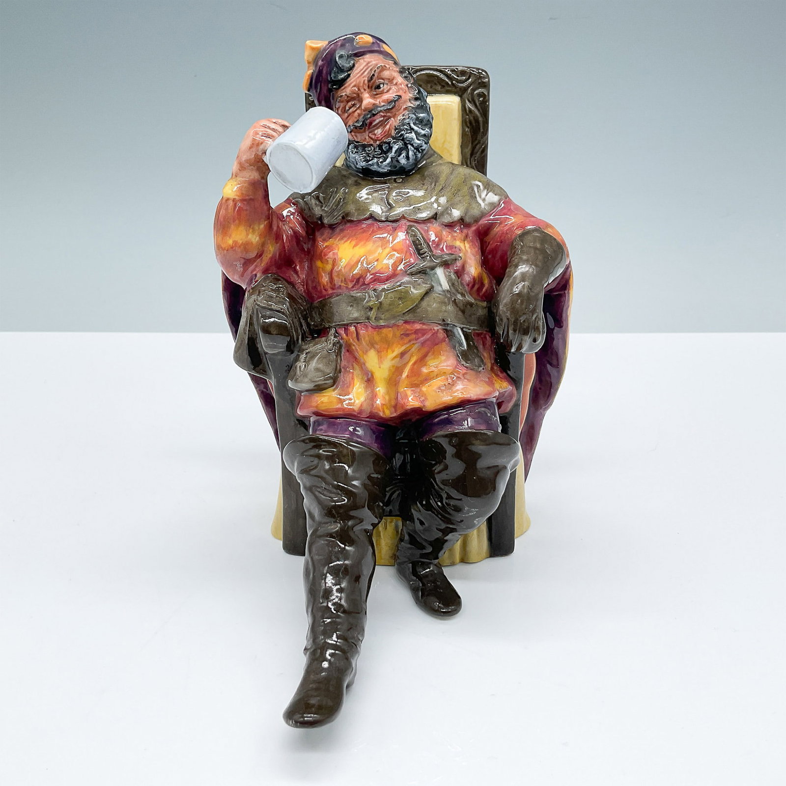 Royal Doulton Figurine, The Foaming Quart HN2162: Royal Doulton figurine titled "The Foaming Quart," model HN2162, issued in 1954. This piece features a cheerful character seated with a mug of ale, dressed in vibrant red and yellow attire. Designed w