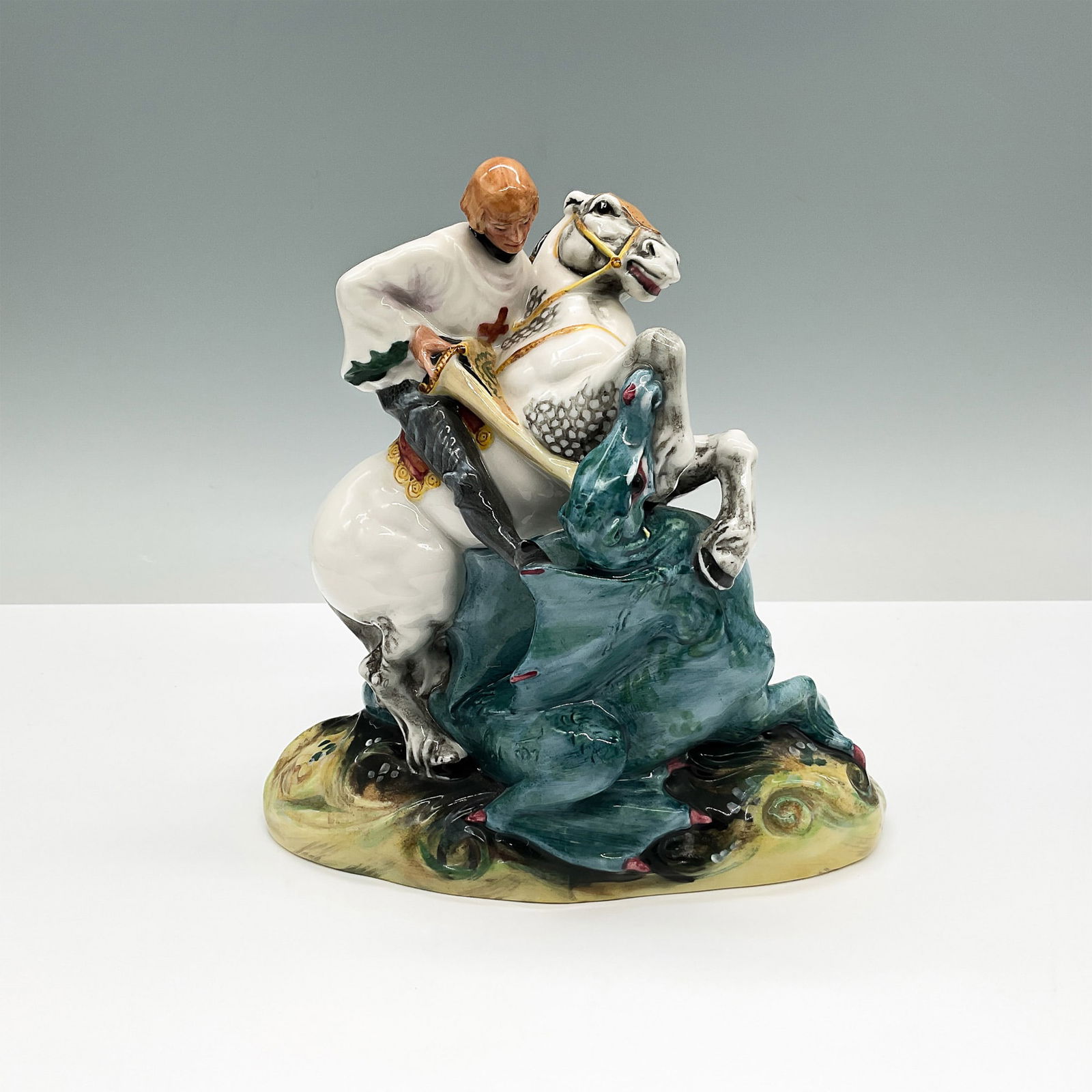 Royal Doulton Porcelain Figurine, St. George, HN2051: This figurine of St. George, designed by Peggy Davies, is a vibrant and highly detailed porcelain figurine depicting St. George in the iconic moment of slaying the dragon. Royal Doulton backstamp and