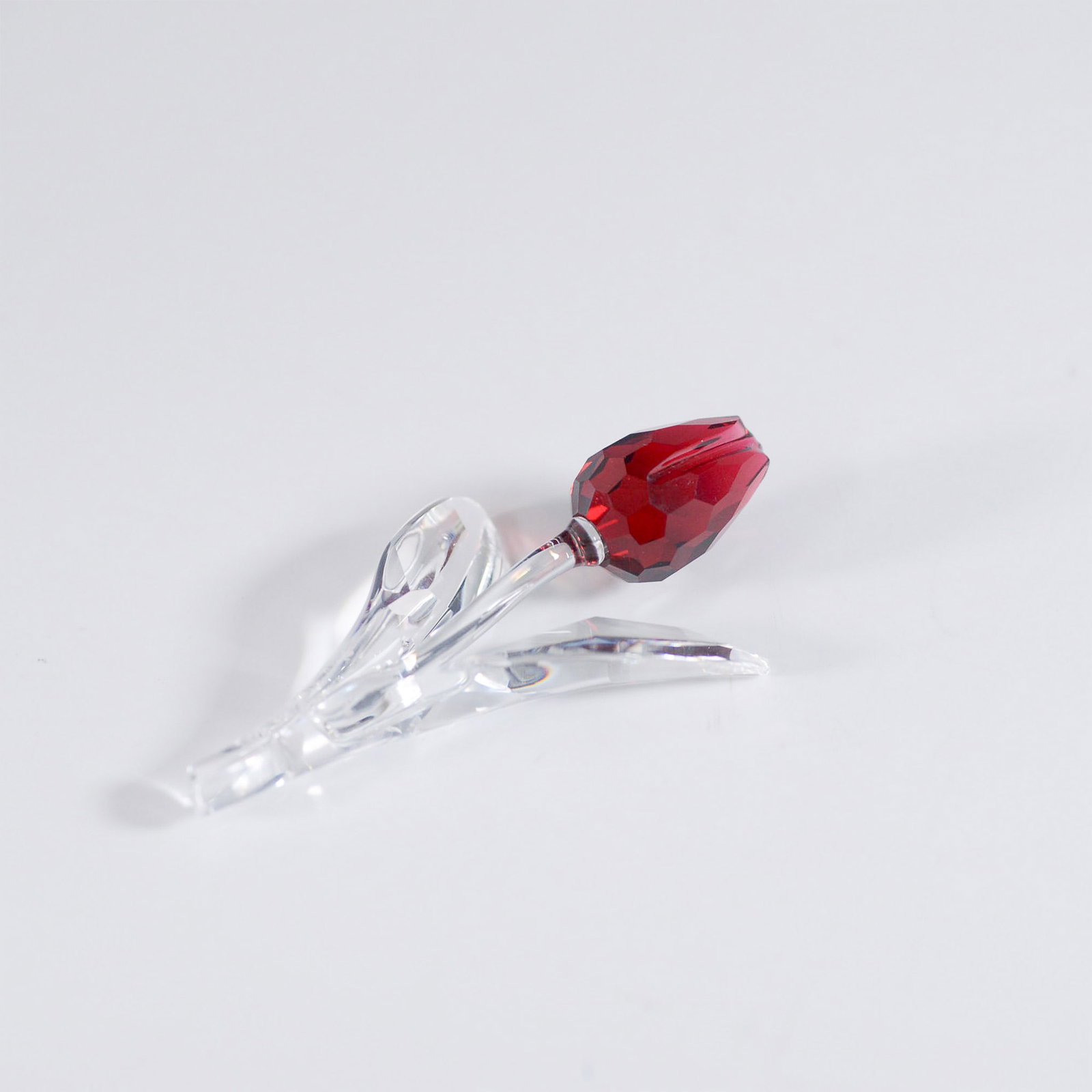 Swarovski Crystal Figurine, Renewal Gift Red Tulip: A Swarovski crystal Red Tulip figurine, model number 626481. This elegant piece features a faceted red crystal tulip bud with a clear crystal stem and leaves, creating a striking contrast. A part of t