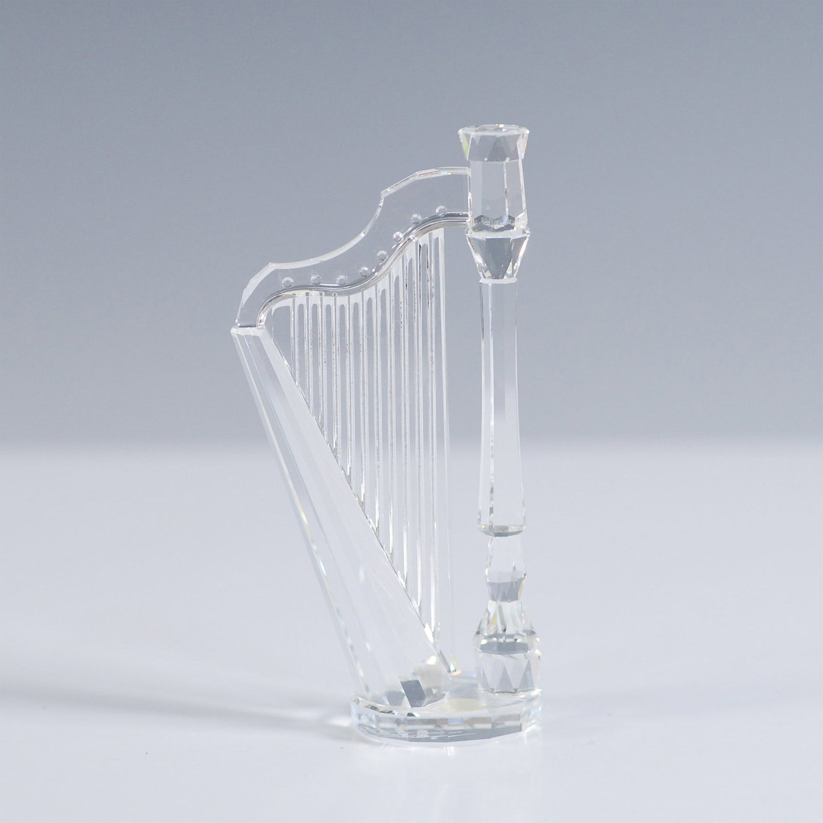 Swarovski Crystal Figurine, Harp, Signed: A finely crafted Swarovski crystal harp figurine from the Crystal Melodies collection, designed by Martin Zendron. Introduced in 1992 and retired in 1998, this elegant piece is made from clear faceted