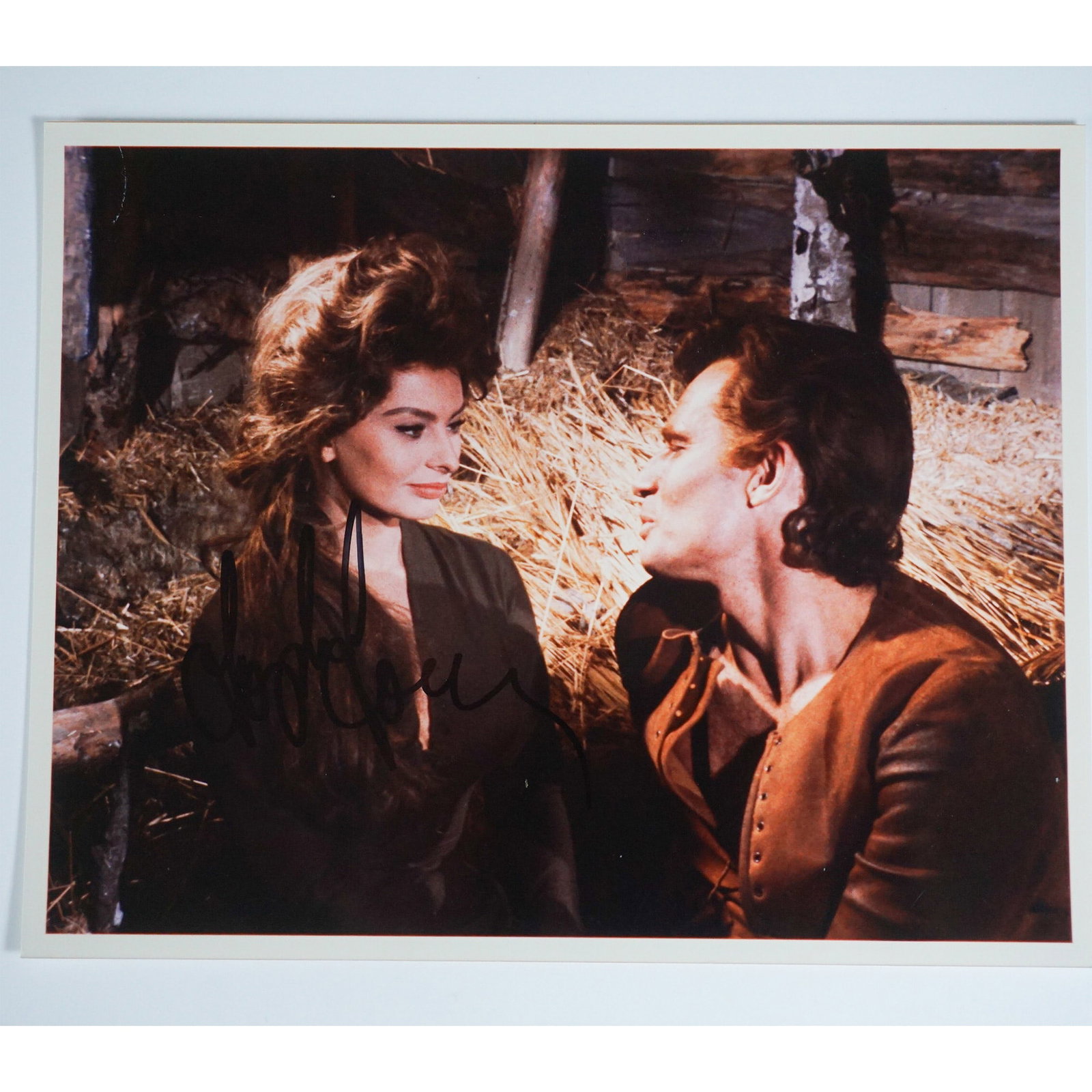 Sophia Loren Autographed Photography from El Cid Film: A vintage color film still from the 1961 historical epic El Cid, starring Sophia Loren and Charlton Heston. The image captures a dramatic moment between the two leads in period costume, set against a 