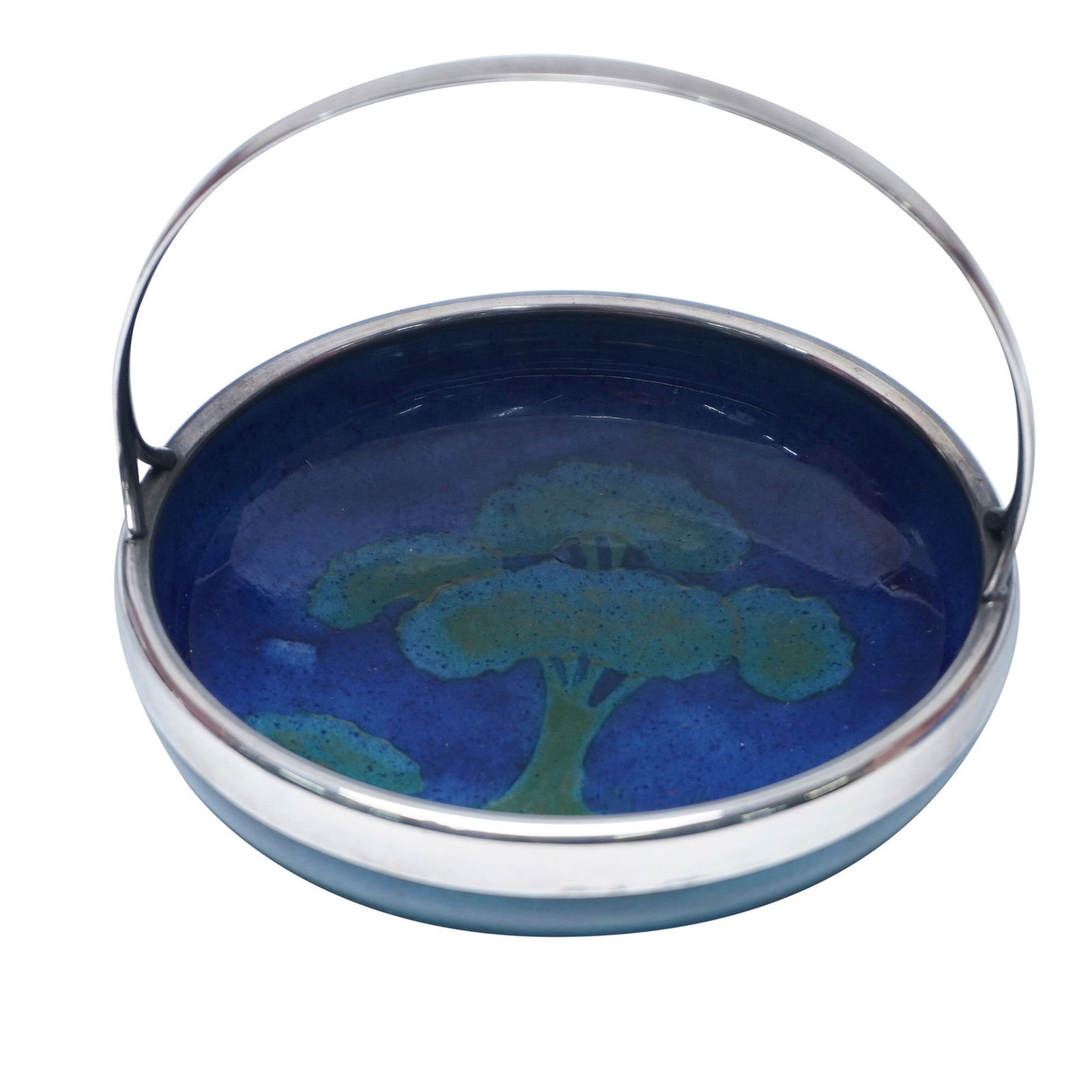 Moorcroft Pottery and Sterling Silver Handle Bowl, Moonlit Blue: A striking ceramic bowl by William Moorcroft, featuring the sought-after 'Moonlit Blue' pattern. This deep blue glaze showcases a hand-painted tree landscape, creating a mesmerizing night scene. The p