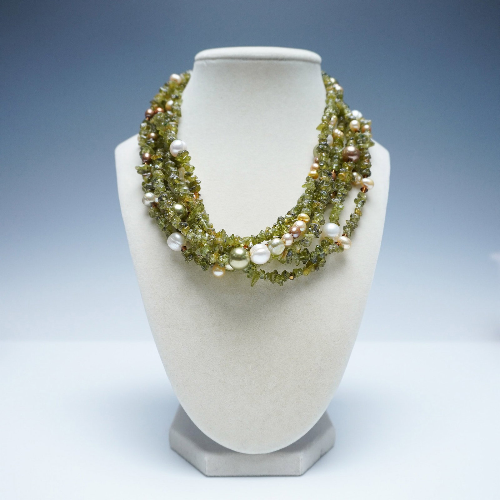Gold-Tone Multi-Strand Necklace with Peridot Chips & Pearls: A stunning multi-strand necklace featuring vibrant green peridot chip beads interwoven with luminous freshwater pearls and gold-tone accents. The mix of textures and colors creates a striking and eleg